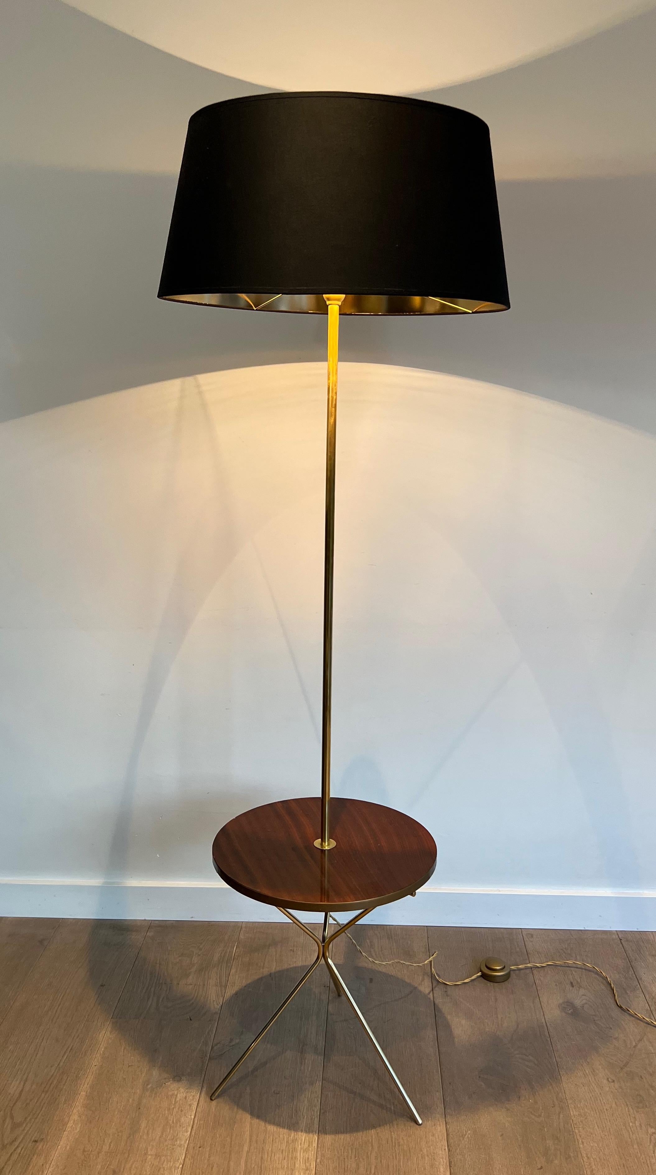 This nice and unusual neoclassical style floor lamp is made of brass with a mahogany round shelf. Thisis a  French work in the style of Maison Jansen. Circa 1940