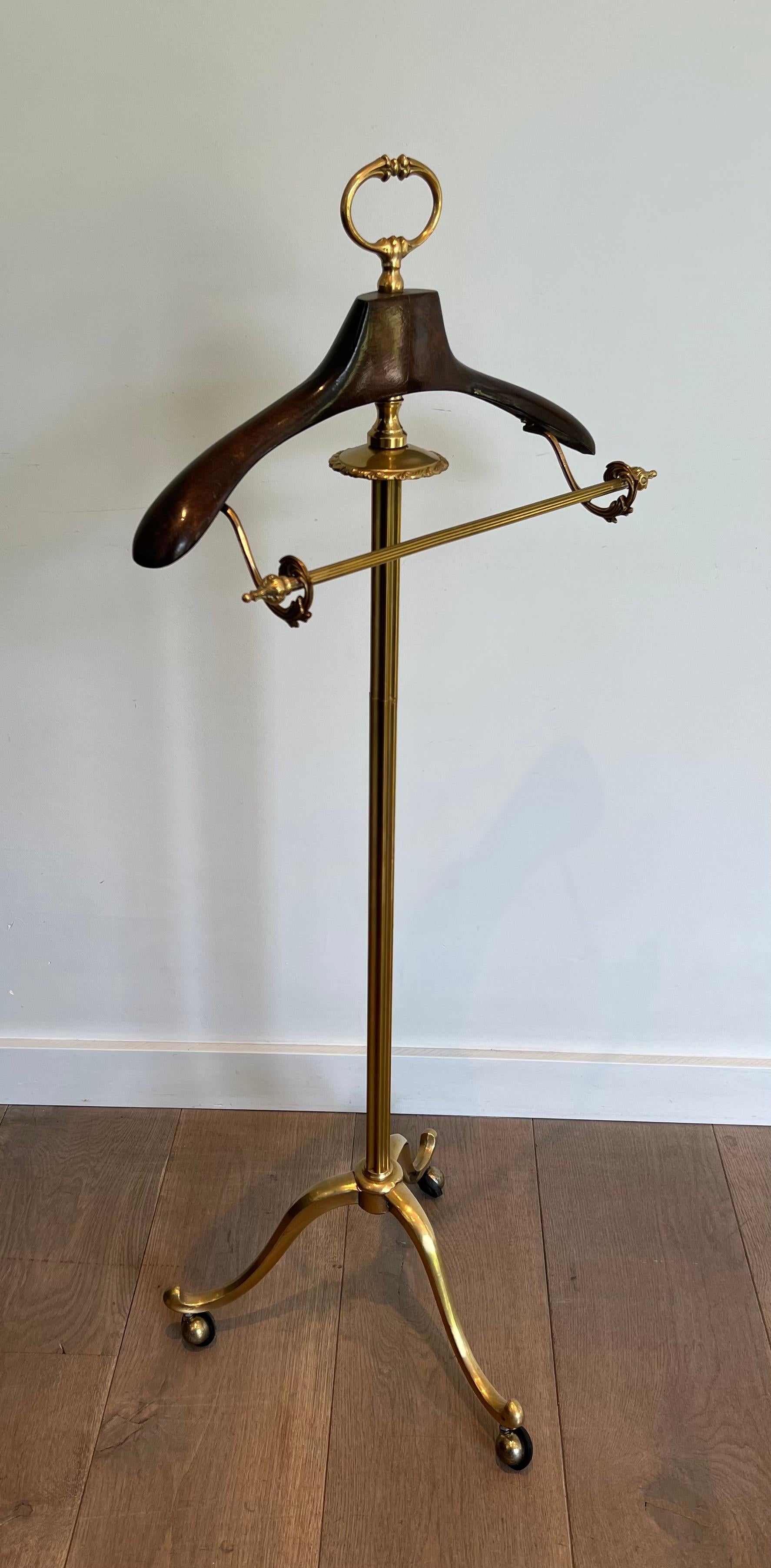 Questo valletto in stile neoclassico è realizzato in ottone e legno con base tripode su rotelle. Questa è un'opera francese. Circa 1940