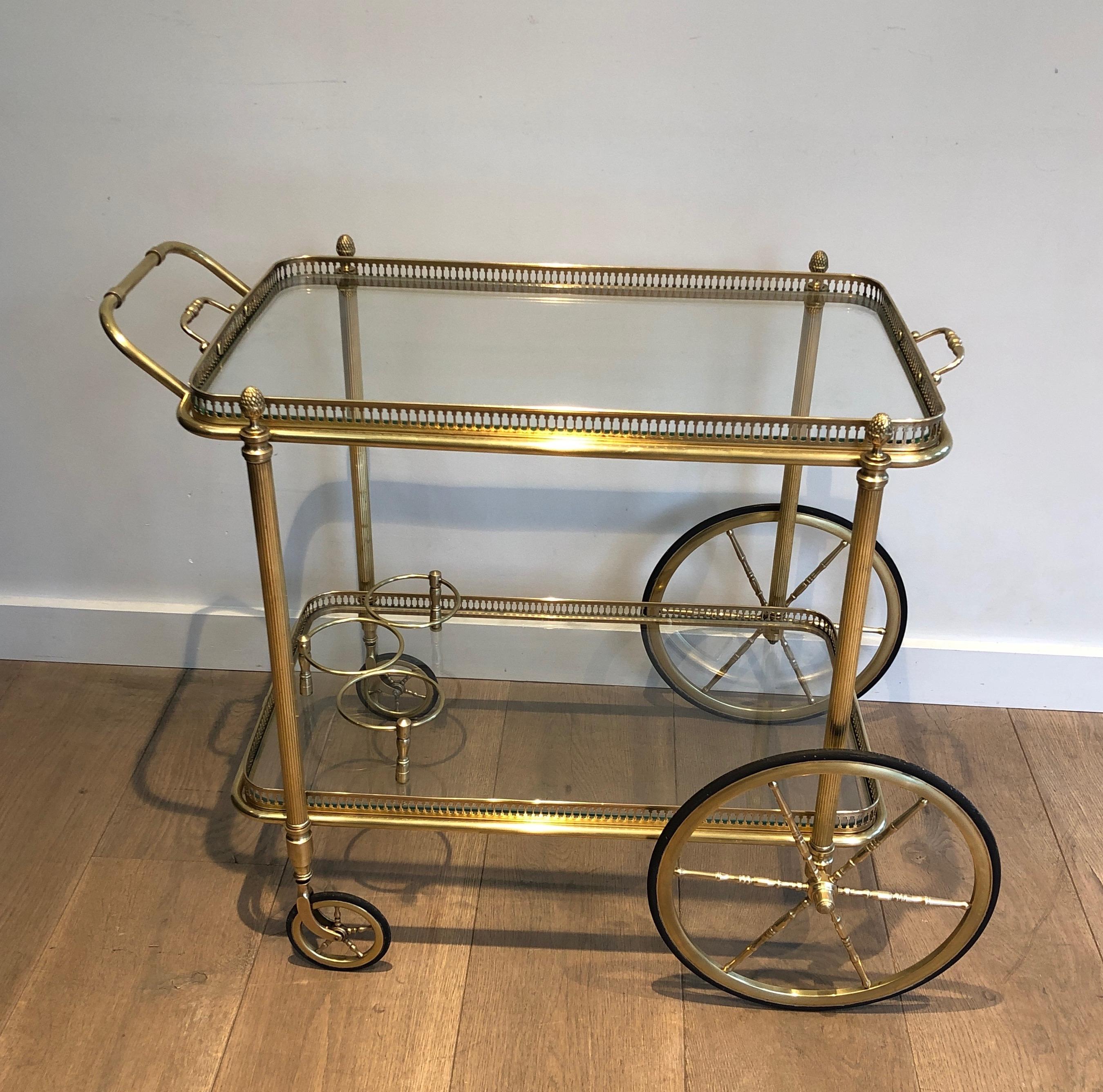 This neoclassical style bar cart is made of brass with removable glass trays. This is a French work by Maison Bagués. Circa 1940.
