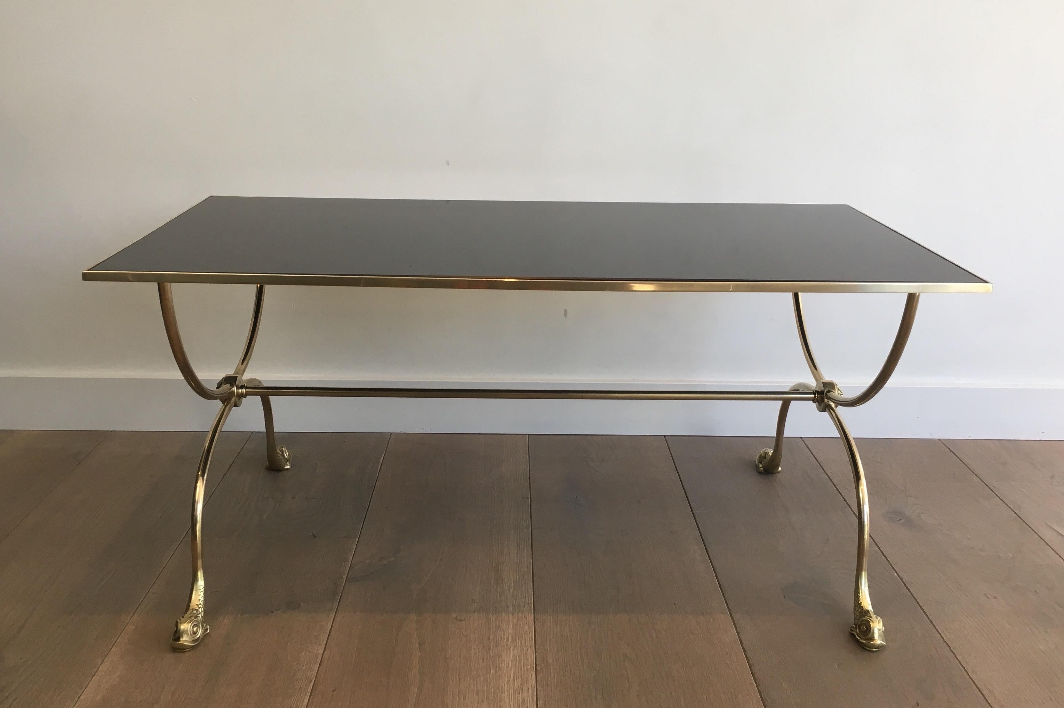 This very nice neoclassical style coffee table is made of brass with dolphin heads feet and a nice mirror shelf. This cocktail was made by famous French designer Maison Jansen, circa 1940.