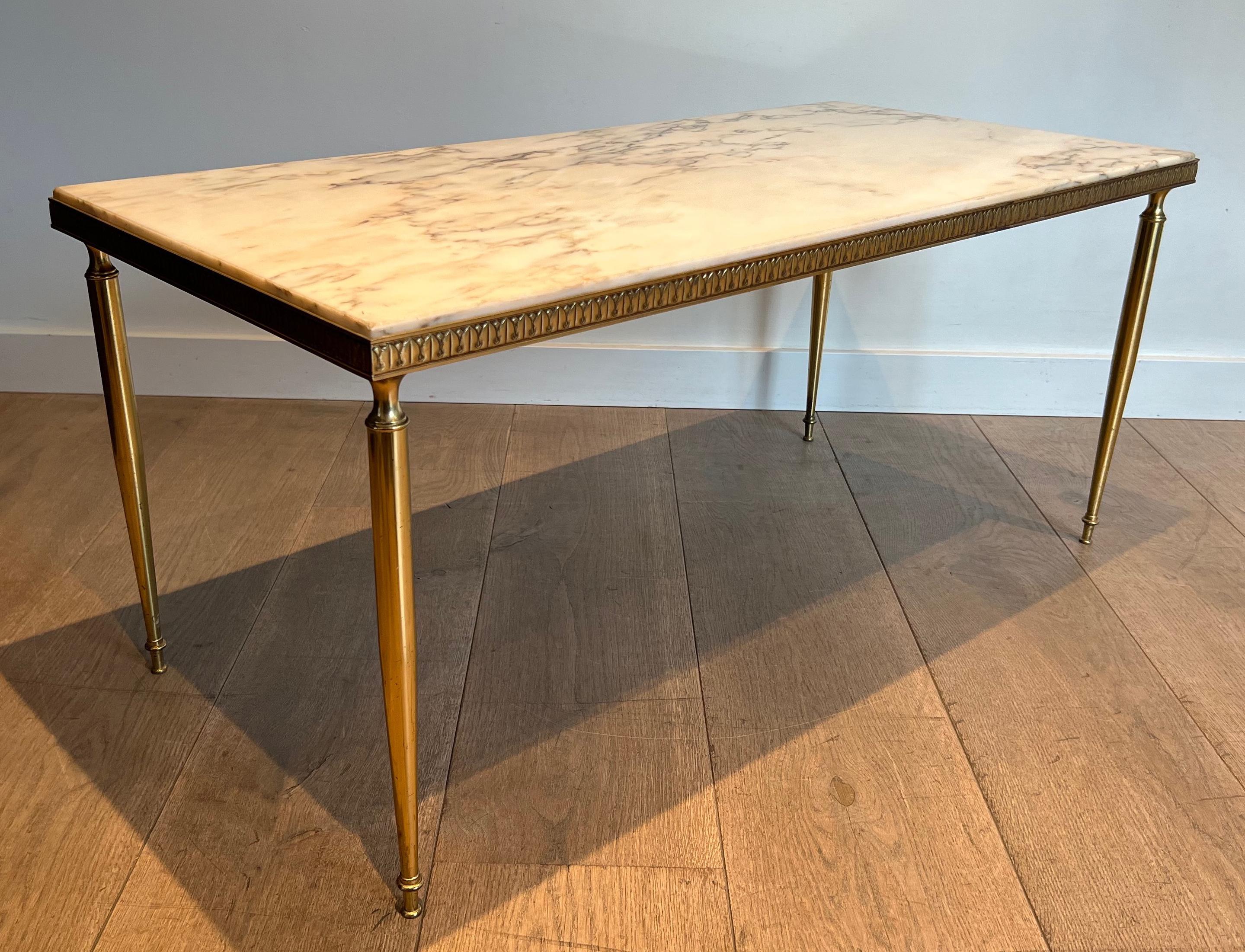 Cette belle table basse de style néoclassique est en laiton avec de jolies décorations tout autour de la galerie entourant le plateau en marbre blanc de Carrare. Il s'agit d'une œuvre française dans le style de la Maison Jansen. Circa 1940