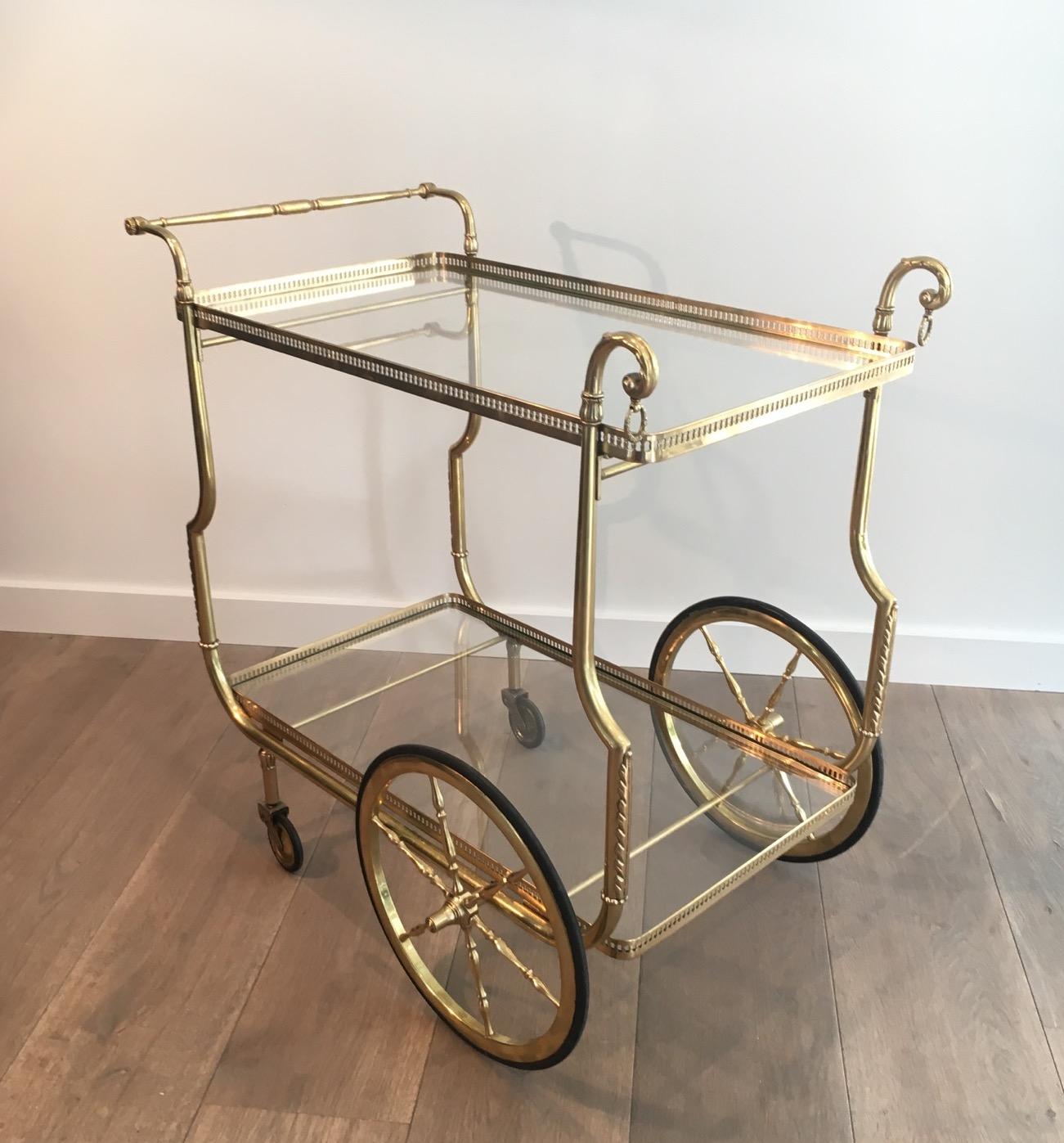 Questo simpatico carrello da bar in stile neoclassico è realizzato in ottone con vassoi in vetro trasparente. Si tratta di un'opera francese di Maison Jansen. Circa 1940
