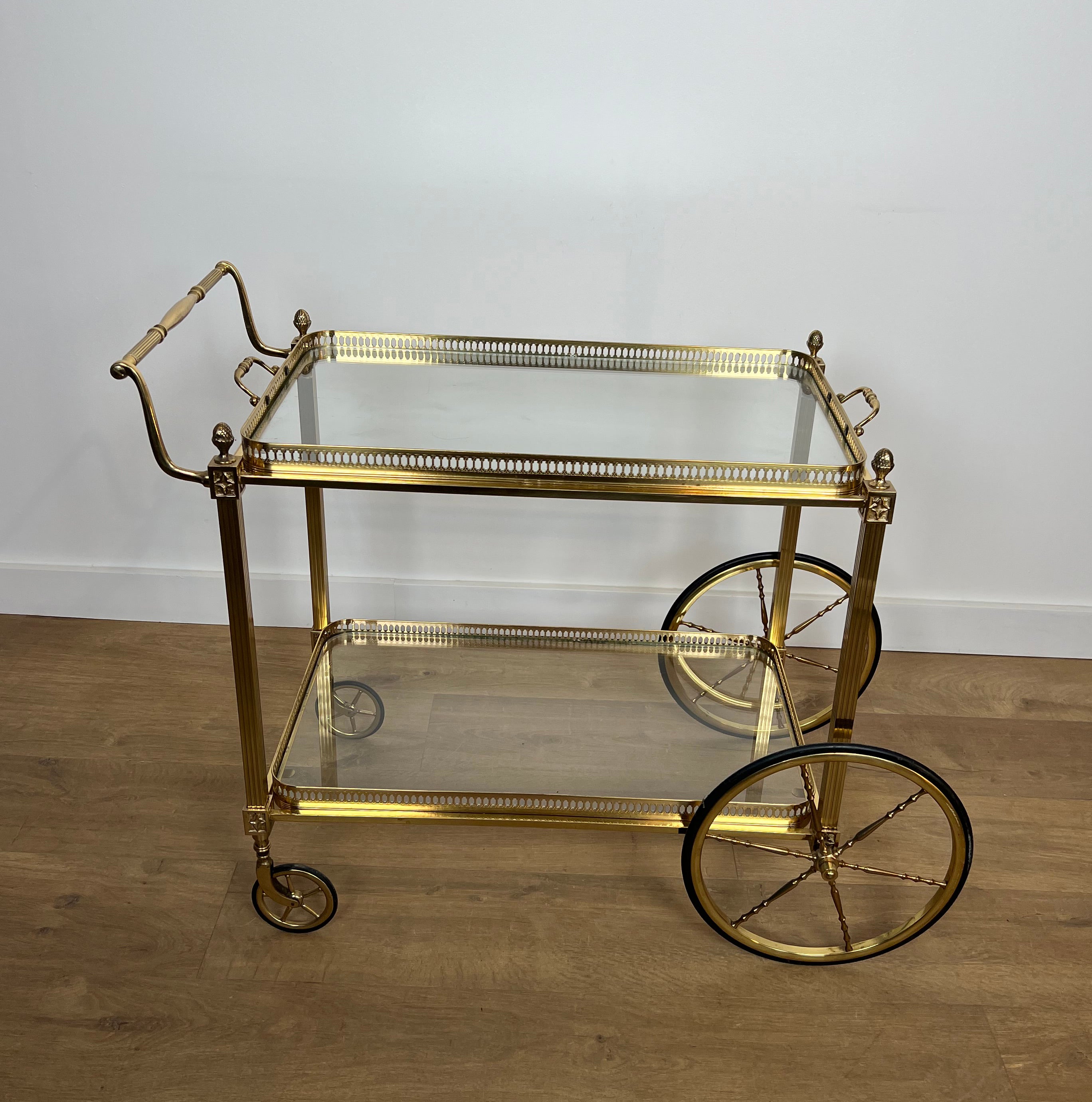 This very elegant neoclassical style bar cart is made of brass with 2 removable glass trays. The drinks trolley is decorated with Lily Flowers. This is a French work by Maison Baguès. Circa 1940.