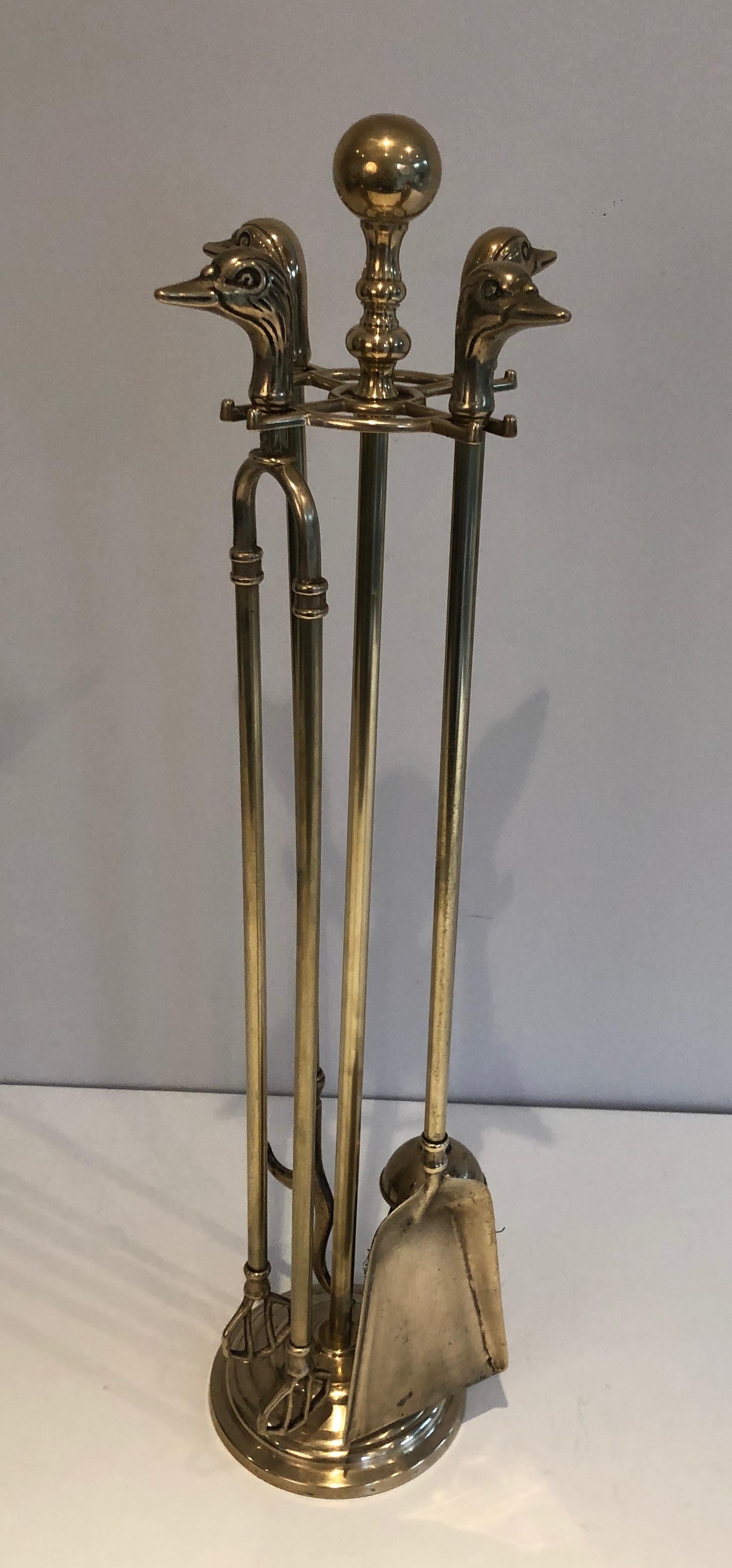 This neoclassical style fireplace tools on stand are made of brass. They have duck heads handles. These are French, circa 1970.
