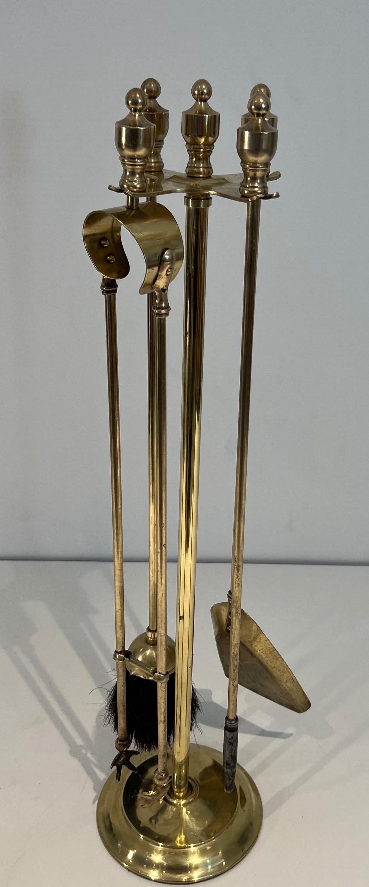 This neoclassical style fireplace tools on stand is made of brass. This is a French work. Circa 1970