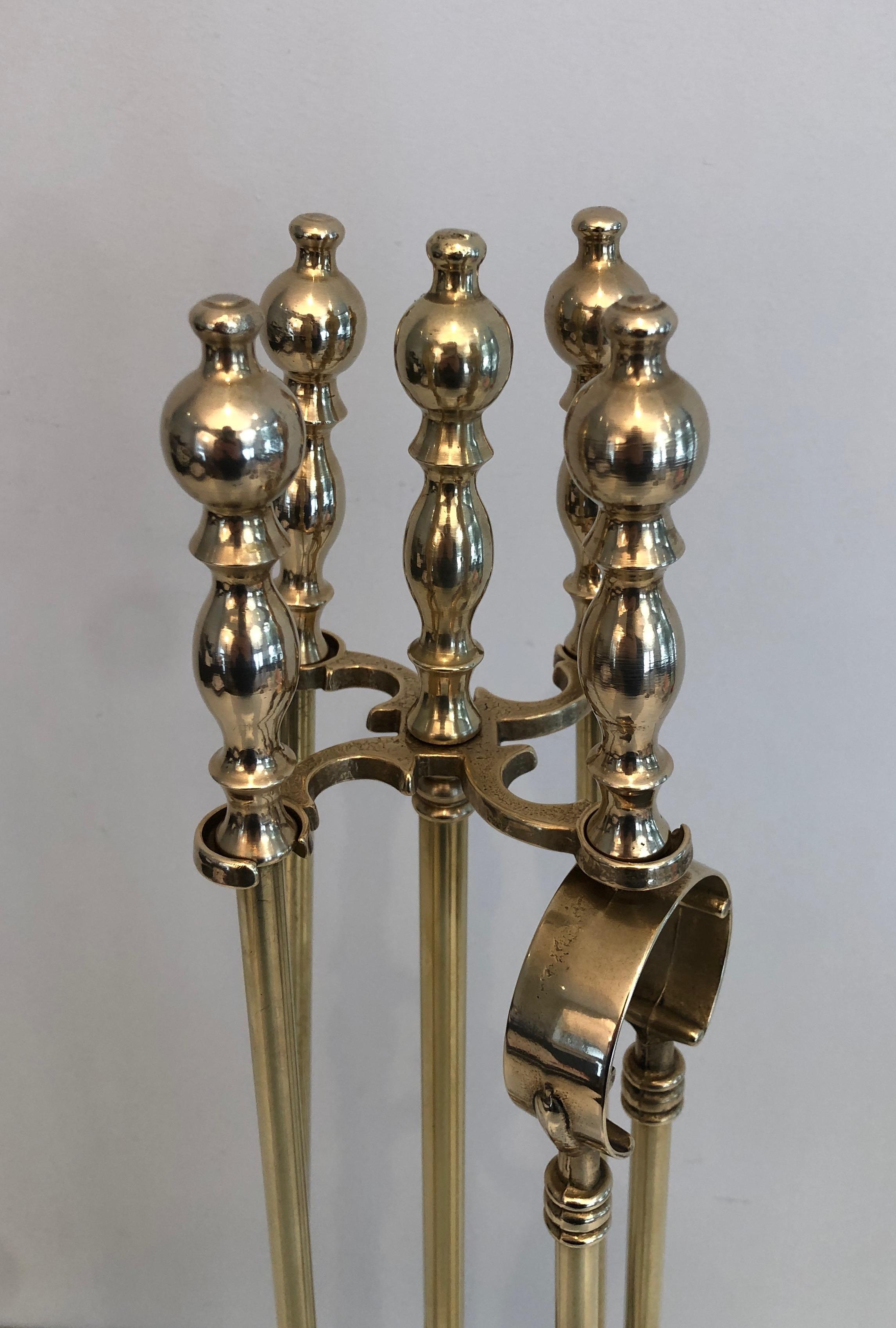 This neoclassical style fireplace tools on stand is made of brass. This is a French work, circa 1970.