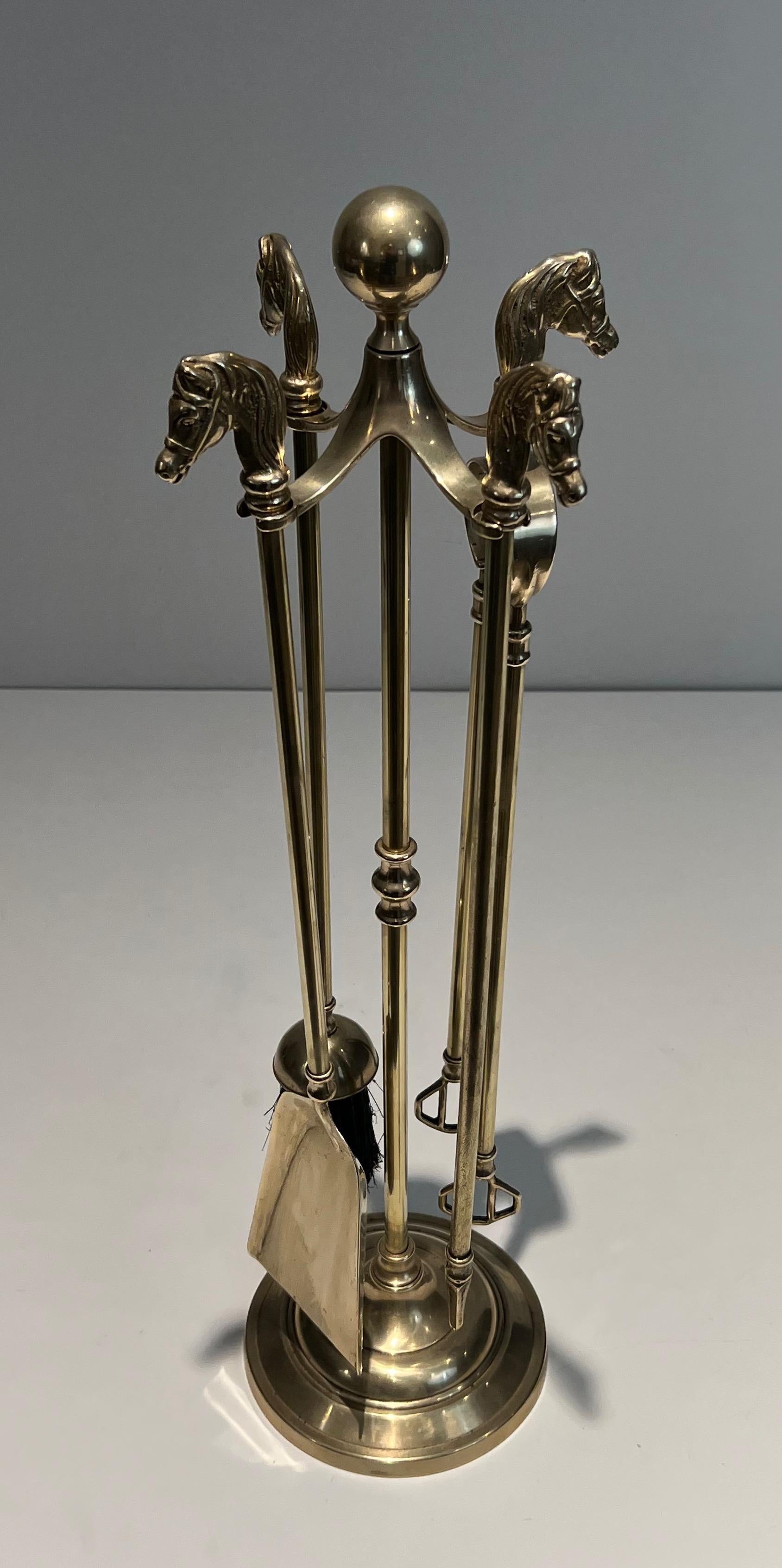 This neoclassical style horseheads fireplace tools on stand is made of brass. This is a French work. Circa 1950.
