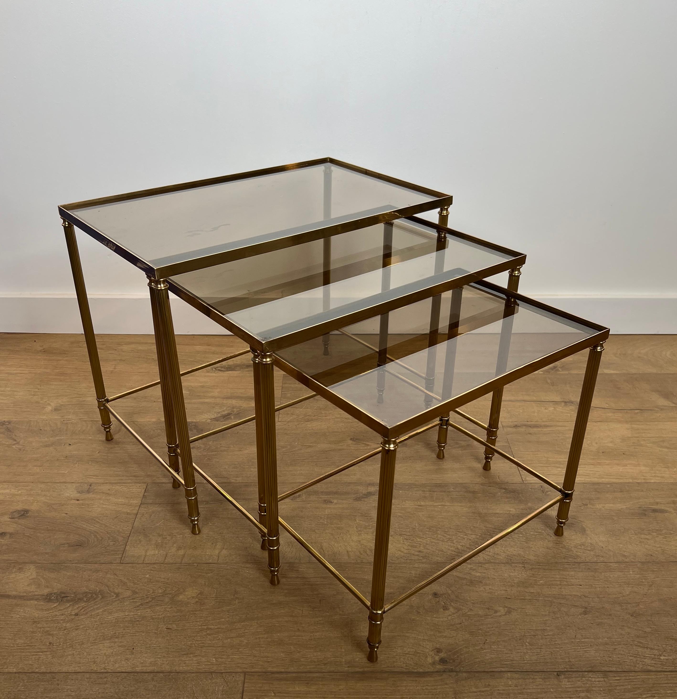 Este bonito conjunto de mesas nido de estilo neoclásico es de latón con tableros de cristal ahumado. Se trata de una obra francesa de la Maison Jansen. Alrededor de 1940