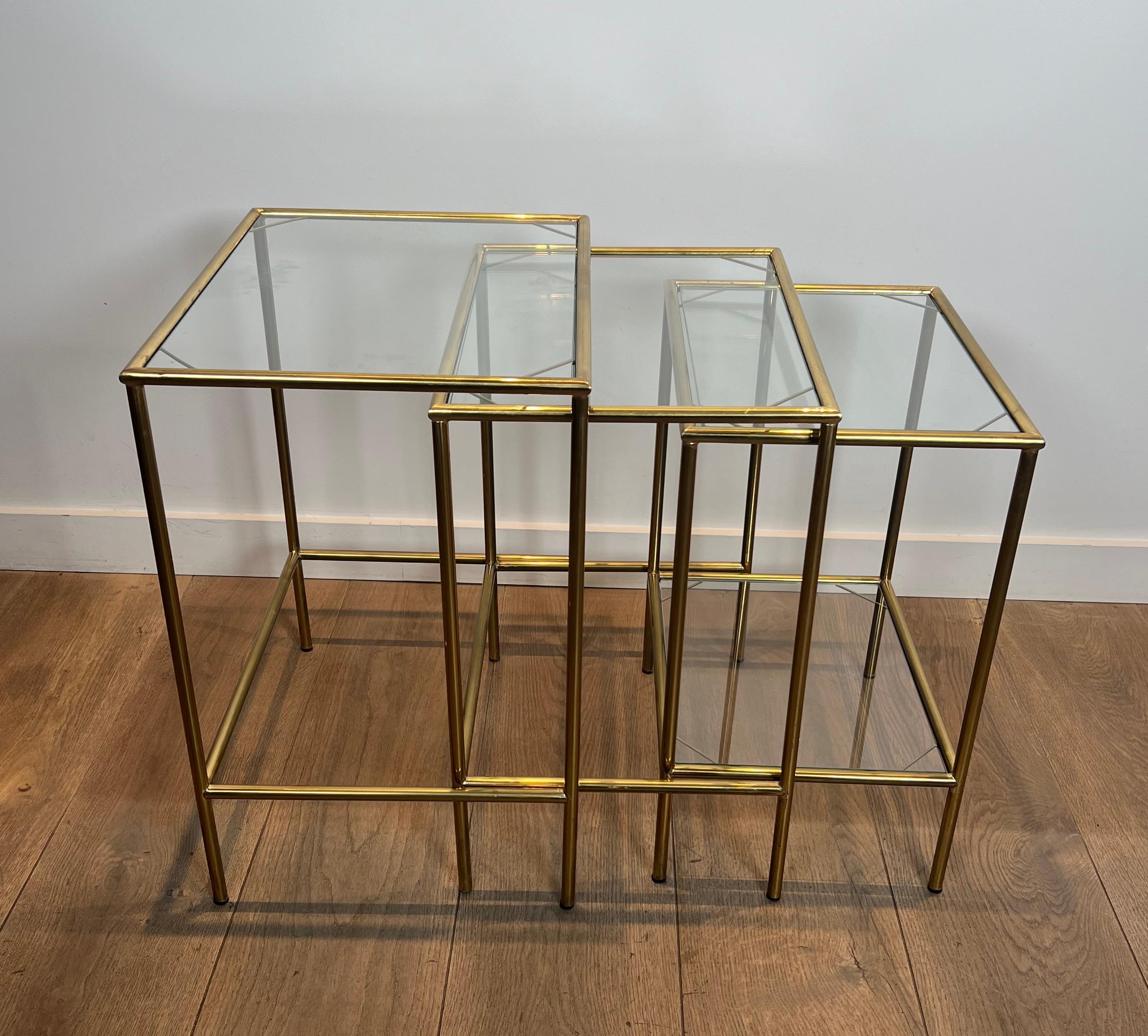 This nice neoclassical style nesting tables are made of brass with glass shelves. This is a French work. Circa 1940