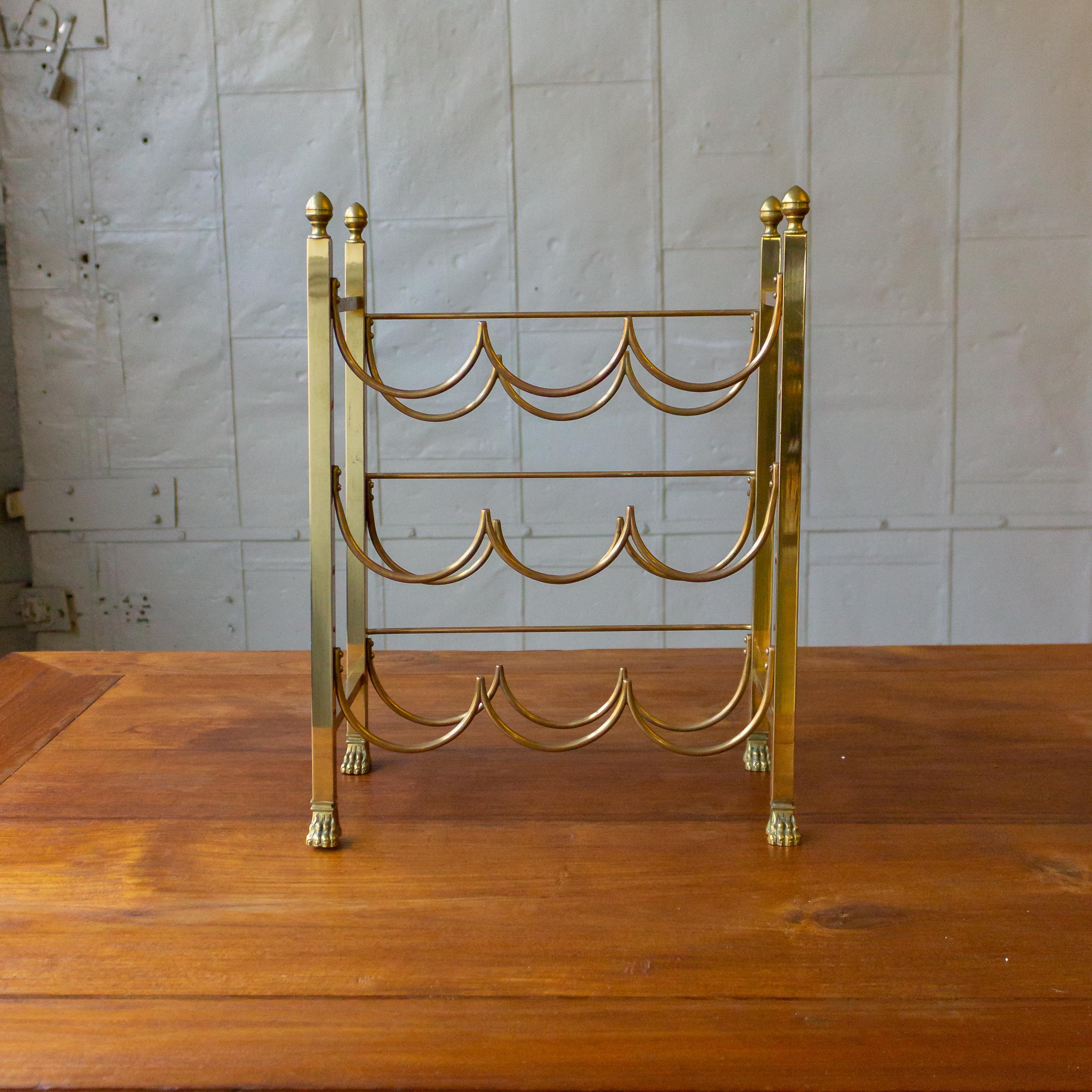 French three-tier polished brass wine rack with claw feet and acorn shaped finials.