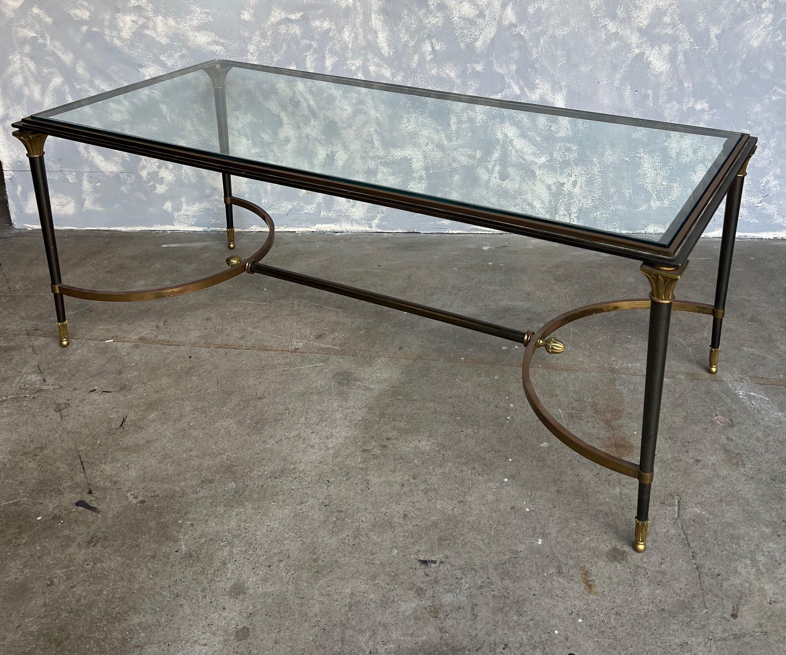 An elegant Italian 1960s Neoclassical style coffee table in the style of Jansen. The table is made of steel with classical gilt bronze decorative elements. The glass table top fits perfectly and the table is secured by a steel stretcher bar with