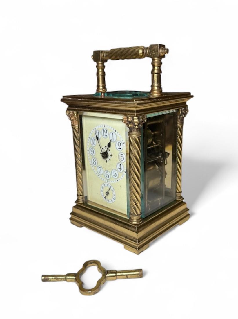 Il s'agit d'une horloge de table/chariot de style néoclassique. Elle représente un coffret rectangulaire en laiton doré dont la façade, semblable à un temple grec, est ornée de deux colonnes corinthiennes surmontées d'une frise. Sous les deux