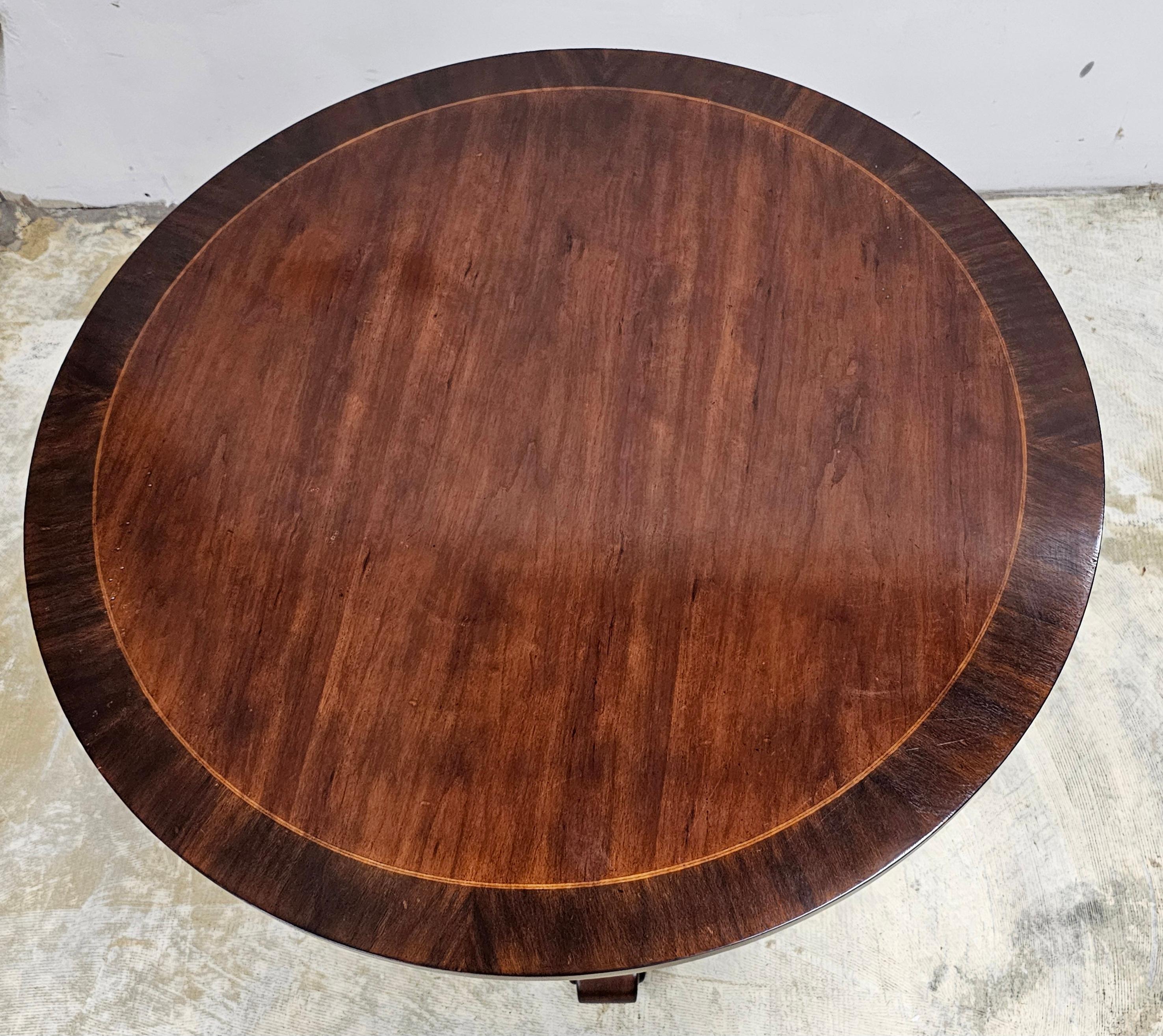 A Neoclassical Style Carved and Cross-Banded Mahogany Pedestal Center Table in great condition. Finely carved pedestal over abtripod feet. Measures 30
