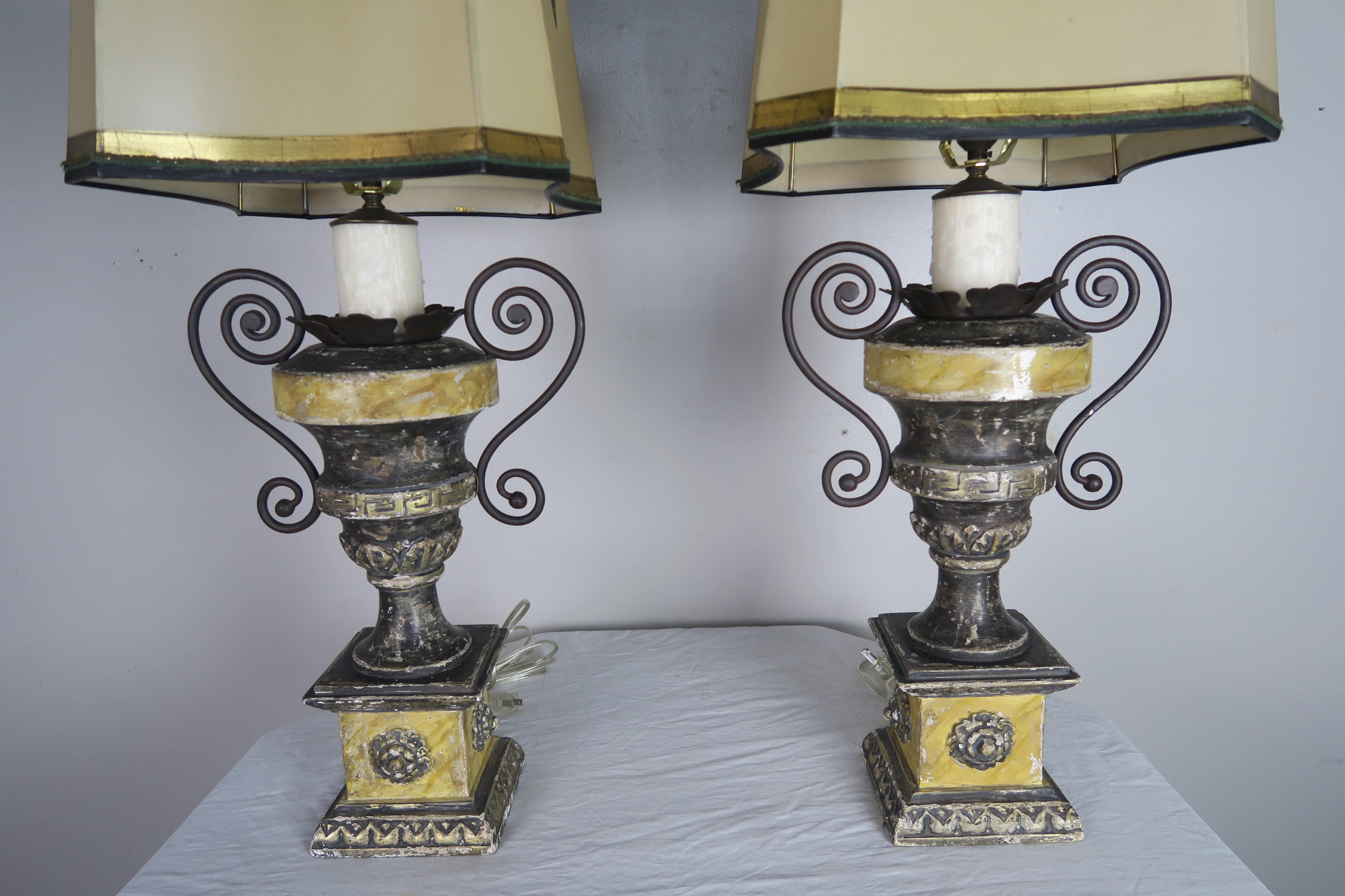 Paire d'urnes de style néoclassique sculptées et peintes, avec rehauts d'argent doré et motif de clé grecque. Les lampes sont nouvellement rebranchées avec des caches-bougies en cire. Les lampes sont couronnées d'abat-jour rectangulaires peints à la