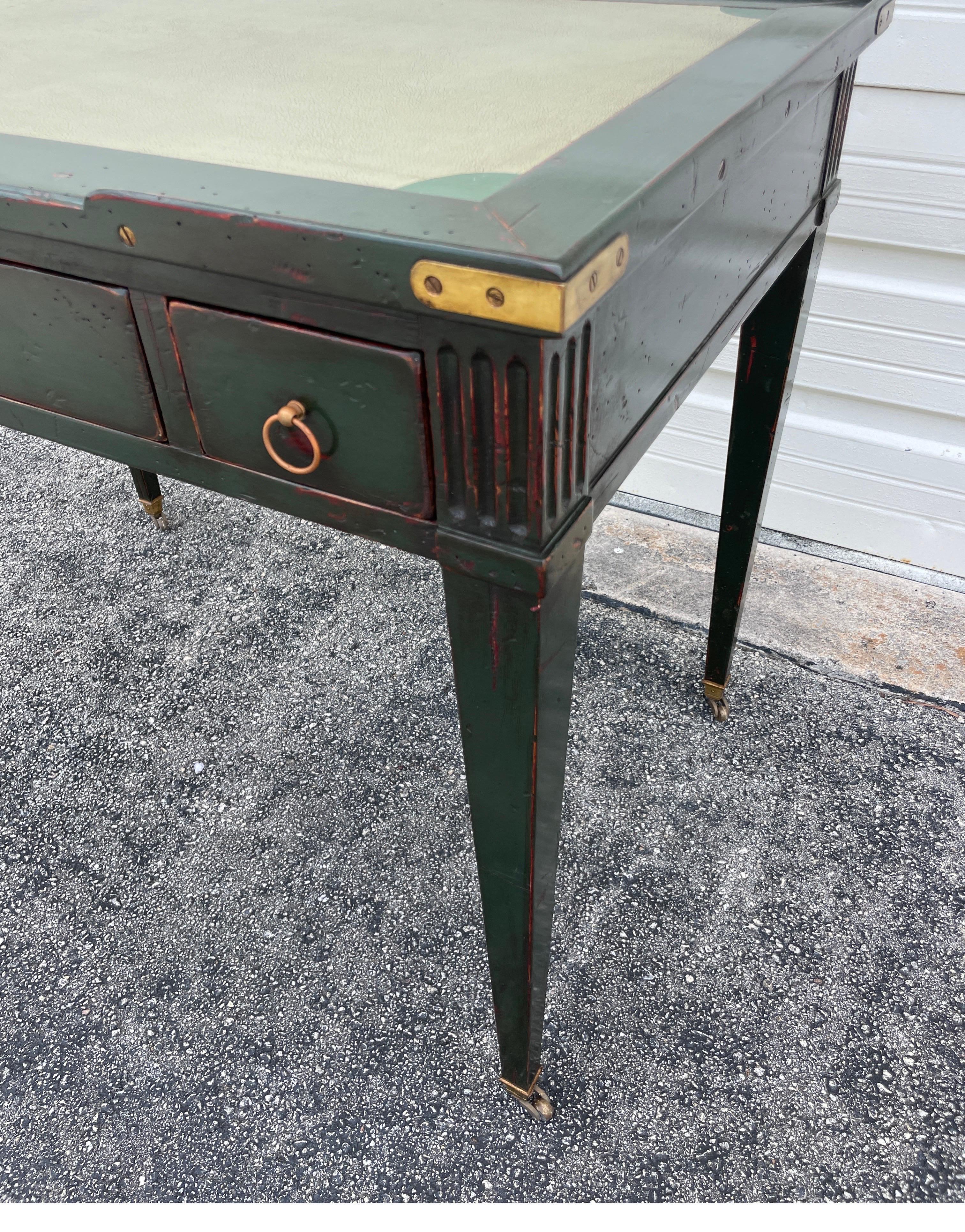Antique French Neoclassica scrivania in pelle con tre cassetti. È rifinito in un colore verde cacciatore verniciato con accenti in ottone. La parte superiore è in pelle verde chiaro.