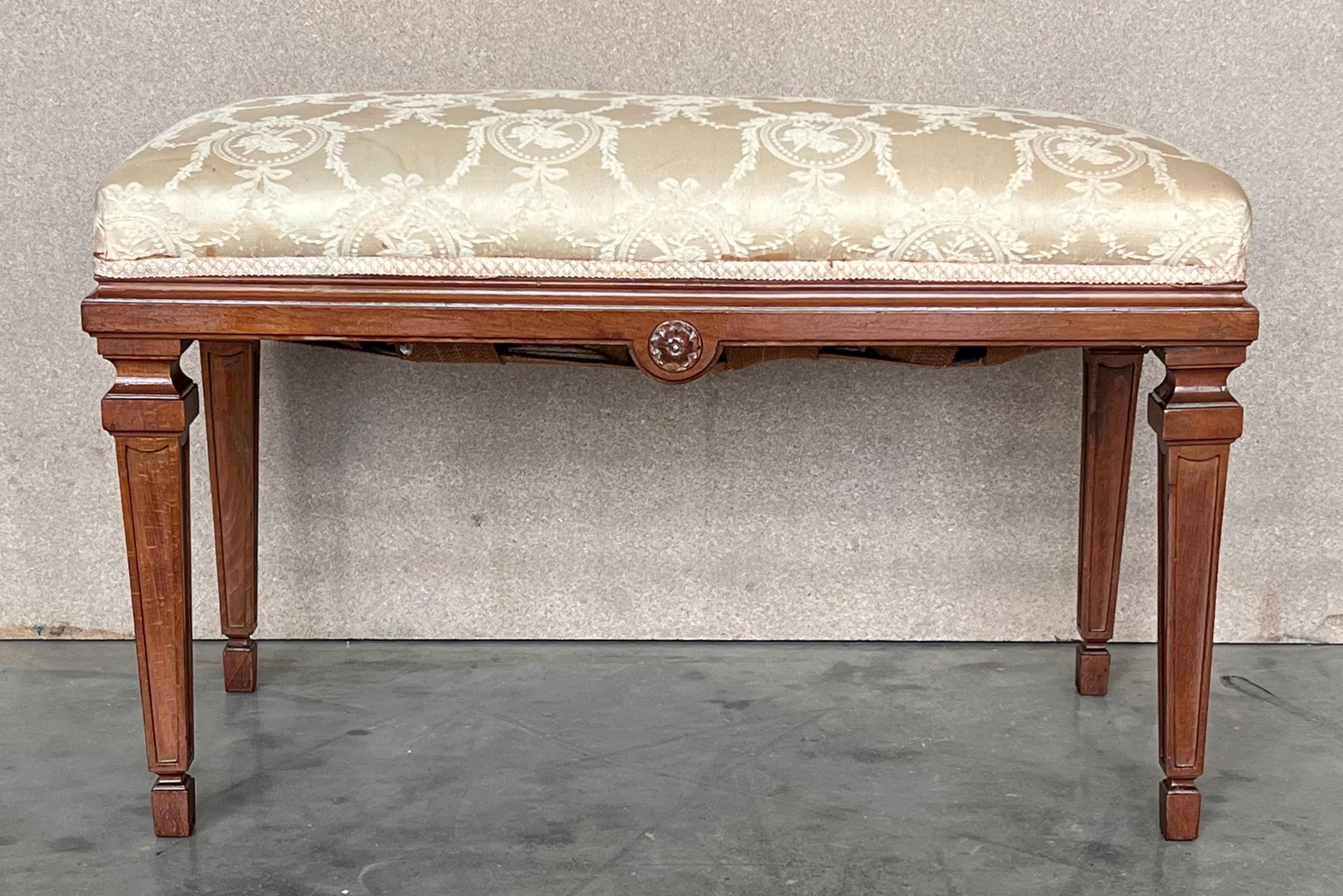 A pair of French Neoclassical style wood benches from the early 20th century, with carved Vitruvian scroll frieze, fluted legs and custom upholstery. This pair of French Neoclassical style wood benches, crafted in the early 20th century, exudes