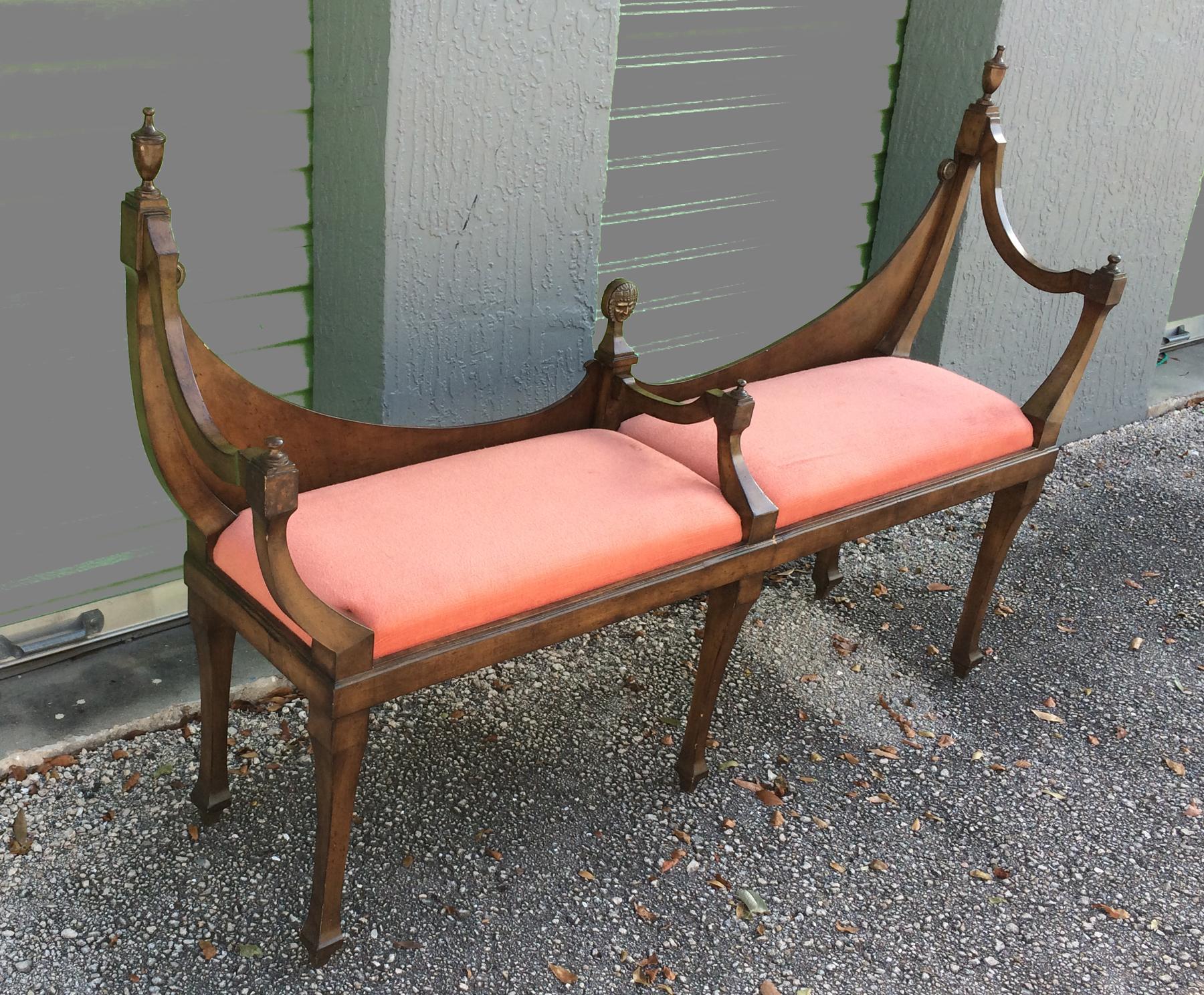 Intriguing fruit-wood bench in the neoclassic style. Inverted double arched back with finials. Scrolled arms, red fabric cushioned seat with tapered square legs. Has a small bronze plaque of a face on the middle back upright.