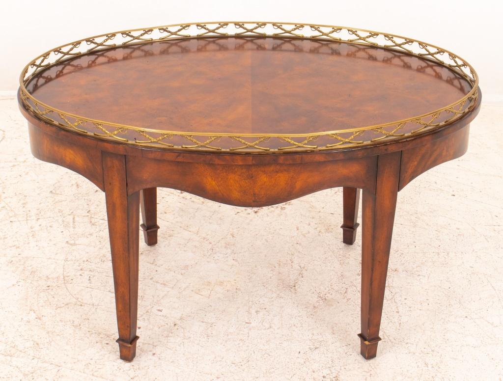 Neoclassical manner gilt bronze galleried oval low table, the gallery with a crossed sabre motif, the heavily figured wood veneered surface above a shaped apron concealing two drawers, one with a faux classical medallion to interior, on four