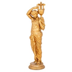 Figura femenina dorada de estilo neoclásico