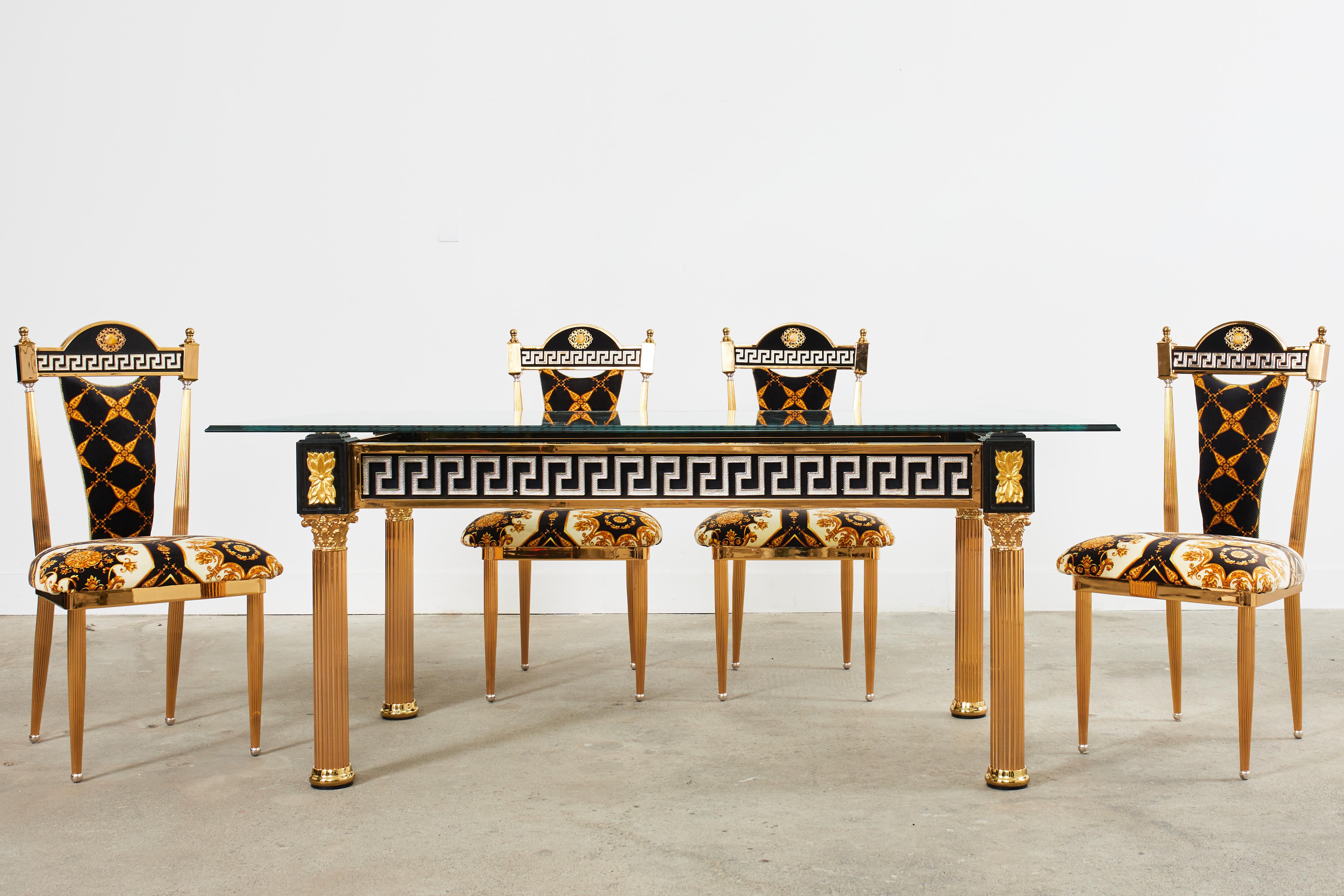 Magnifique table de salle à manger en or ou en verre doré d'après Versace. Réalisé dans le goût néoclassique avec des pieds cannelés en forme de colonne grecque de style corinthien. La base de la table est décorée de motifs de style clé grecque