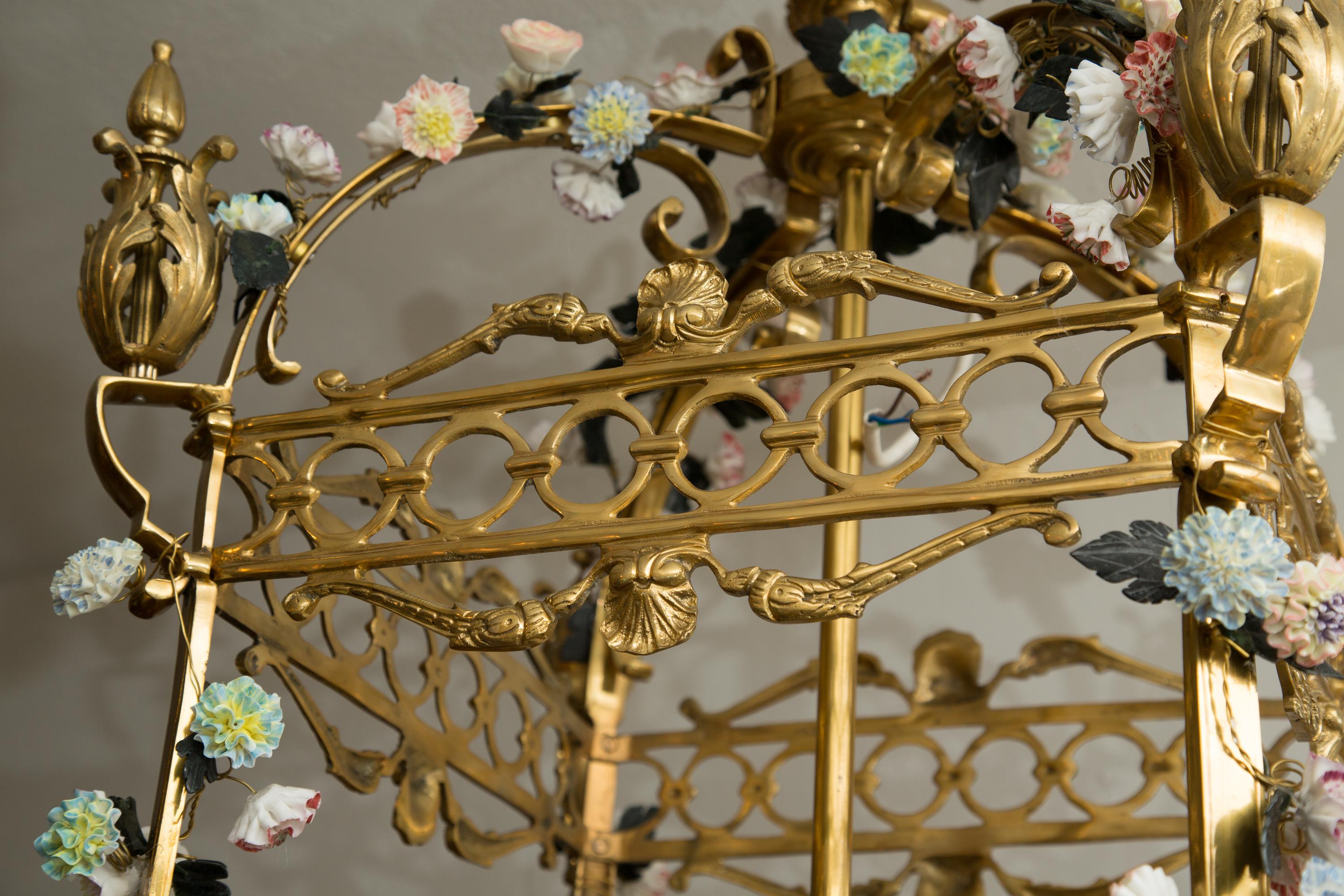 This is a very romantic neoclassical style gilt bronze lantern-form chandelier-encrusted overall with a plethora of multicolored porcelain flower heads, early 20th century.