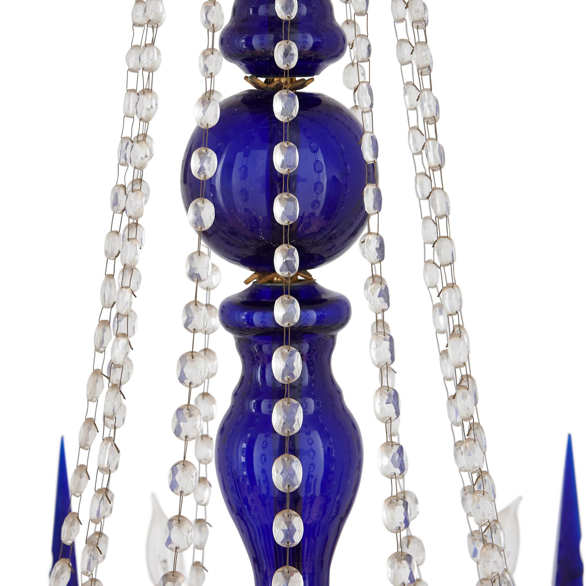This magnificent chandelier is composed of a variety of media, which beautifully contrast in their colour and qualities. This includes lustrous golden gilt bronze (ormolu), cut clear glass, and smooth cobalt blue glass. The chandelier will make a