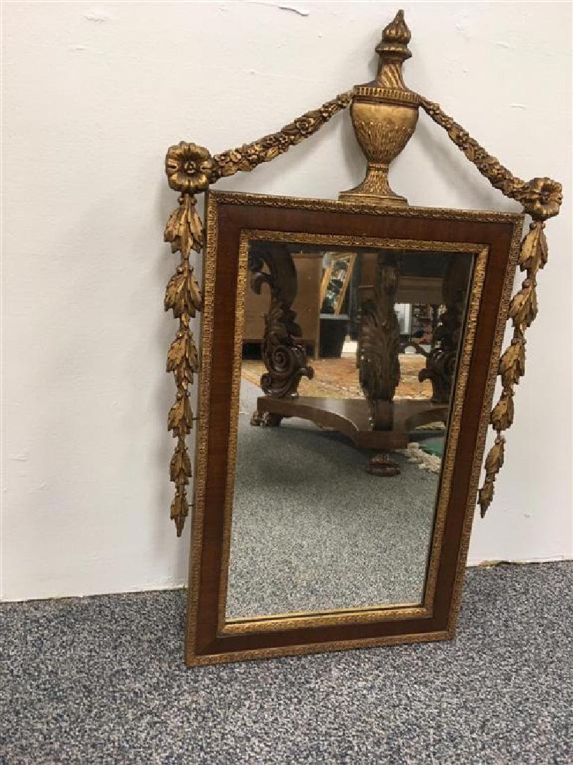 Neoklassizistischer Spiegel aus Giltwood und Mahagoni mit Ornamenten. Aufwendig geschnitzter Spiegel aus Mahagoni und vergoldetem Holz. Auf der Oberseite befindet sich ein erhaben montiertes klassisches Urnenwappen. Von der Urne aus ziehen sich