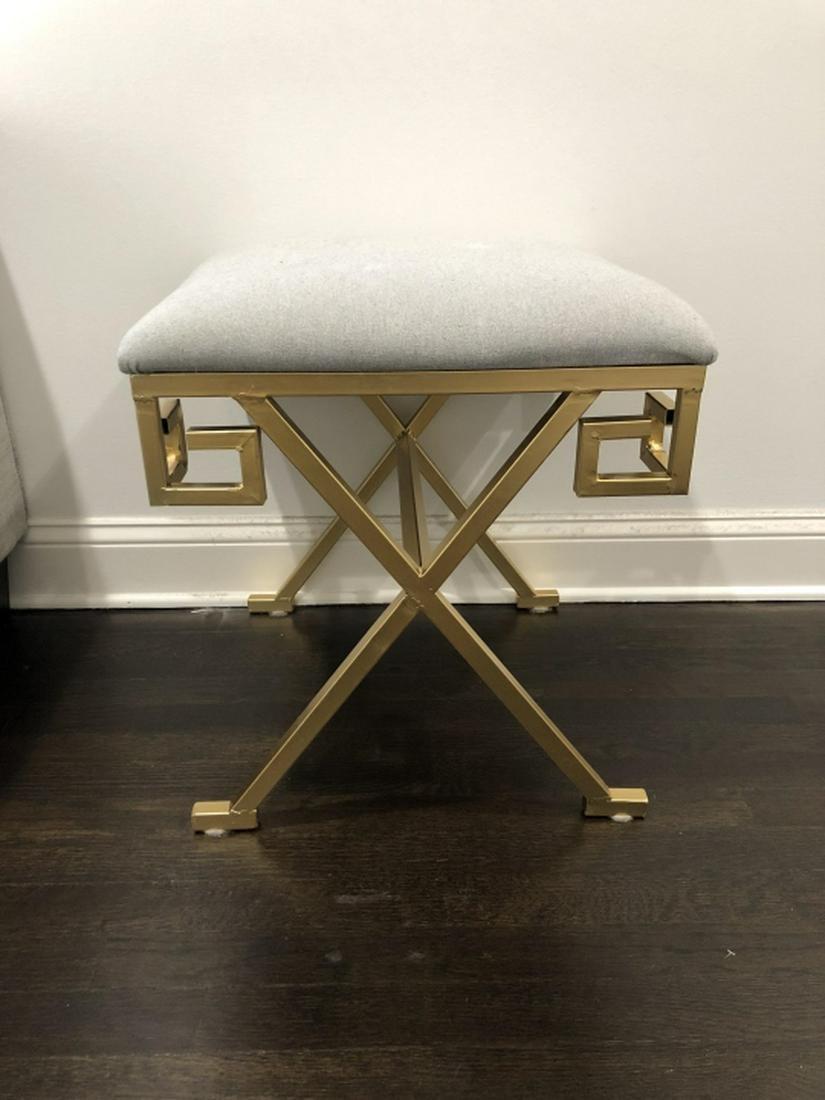 In the style of Jean-Michel Frank, this modern gilt metal upholstered Greek key X-form base vanity bench or stool. Each corner of the bench forms a Greek key motif with crossed legs and stretcher. Gilt metal with upholstered cushion top.