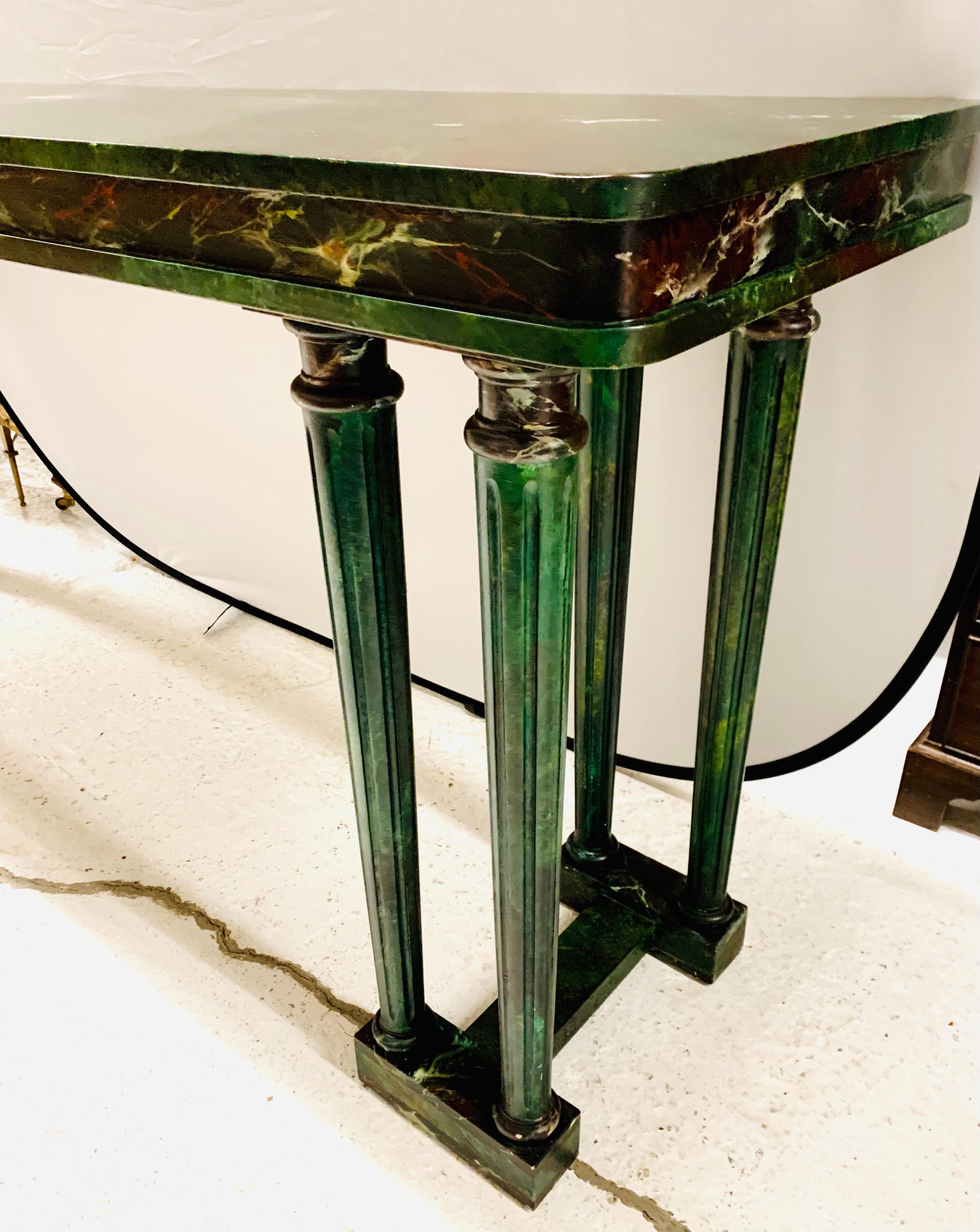 Neoclassical style console table has been hand painted in a faux green marble finish. It rests on eight painted column supports.