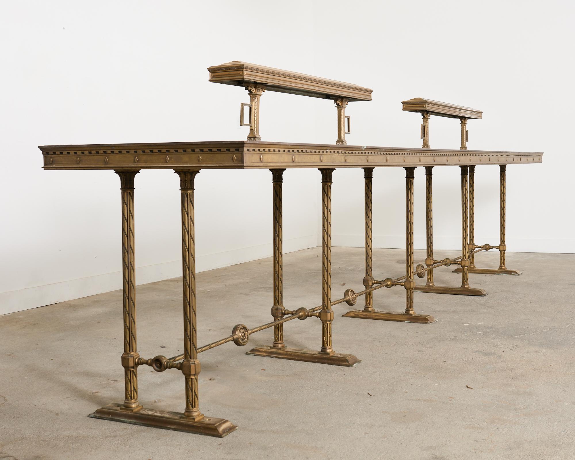 Monumental industrial bronze bar height counter measuring nearly 16 feet long. The bar height table crafted in the neoclassical taste was formerly a bank lobby counter with two sets of lights running down the middle. Incredibly heavy and solid with