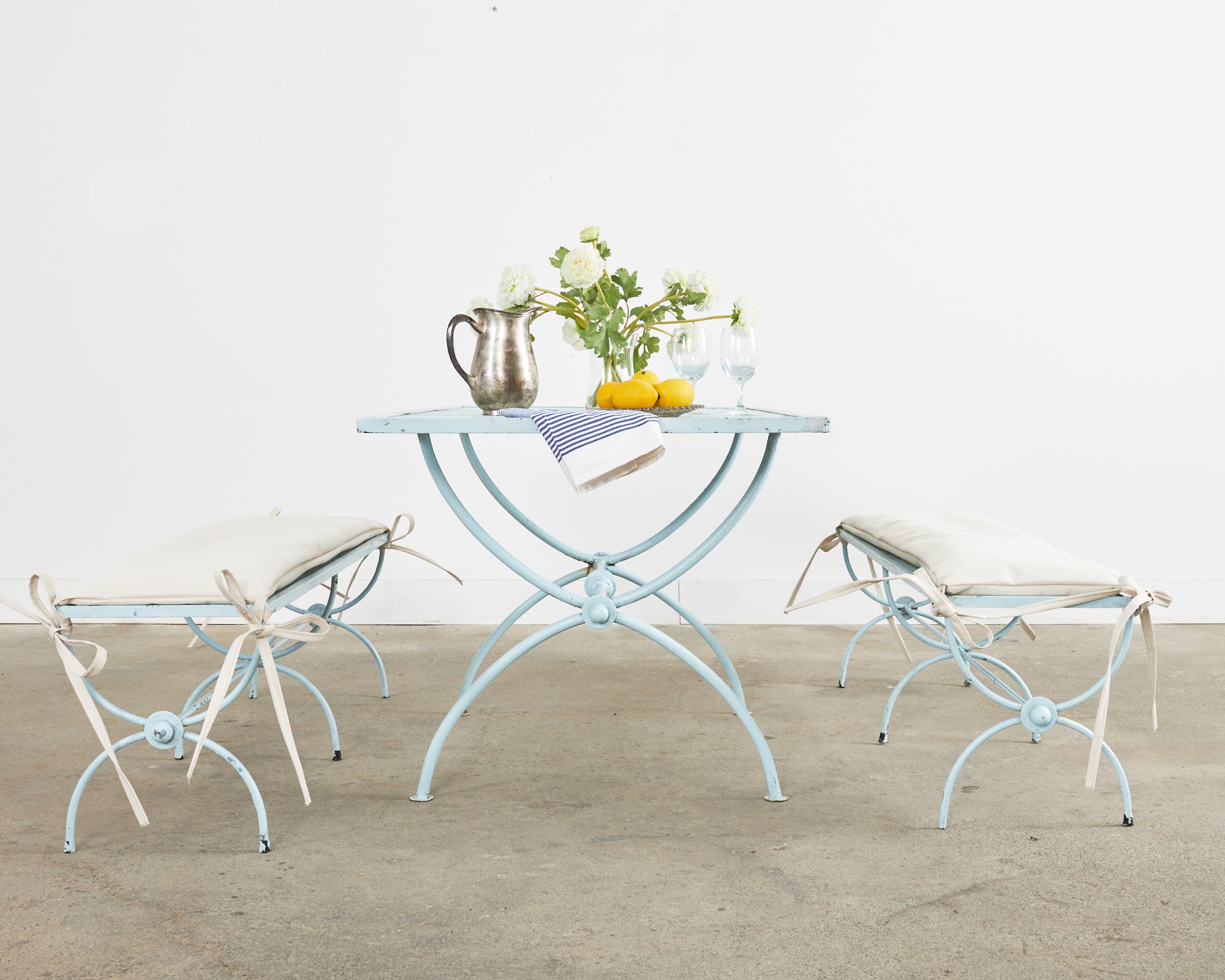 Mid-Century Modern painted iron patio and garden table featuring neoclassical style Curule legs. The top of the rectangular garden table has a mesh inset in a geometric pattern. The table is supported by a trestle-style base with gracefully curved