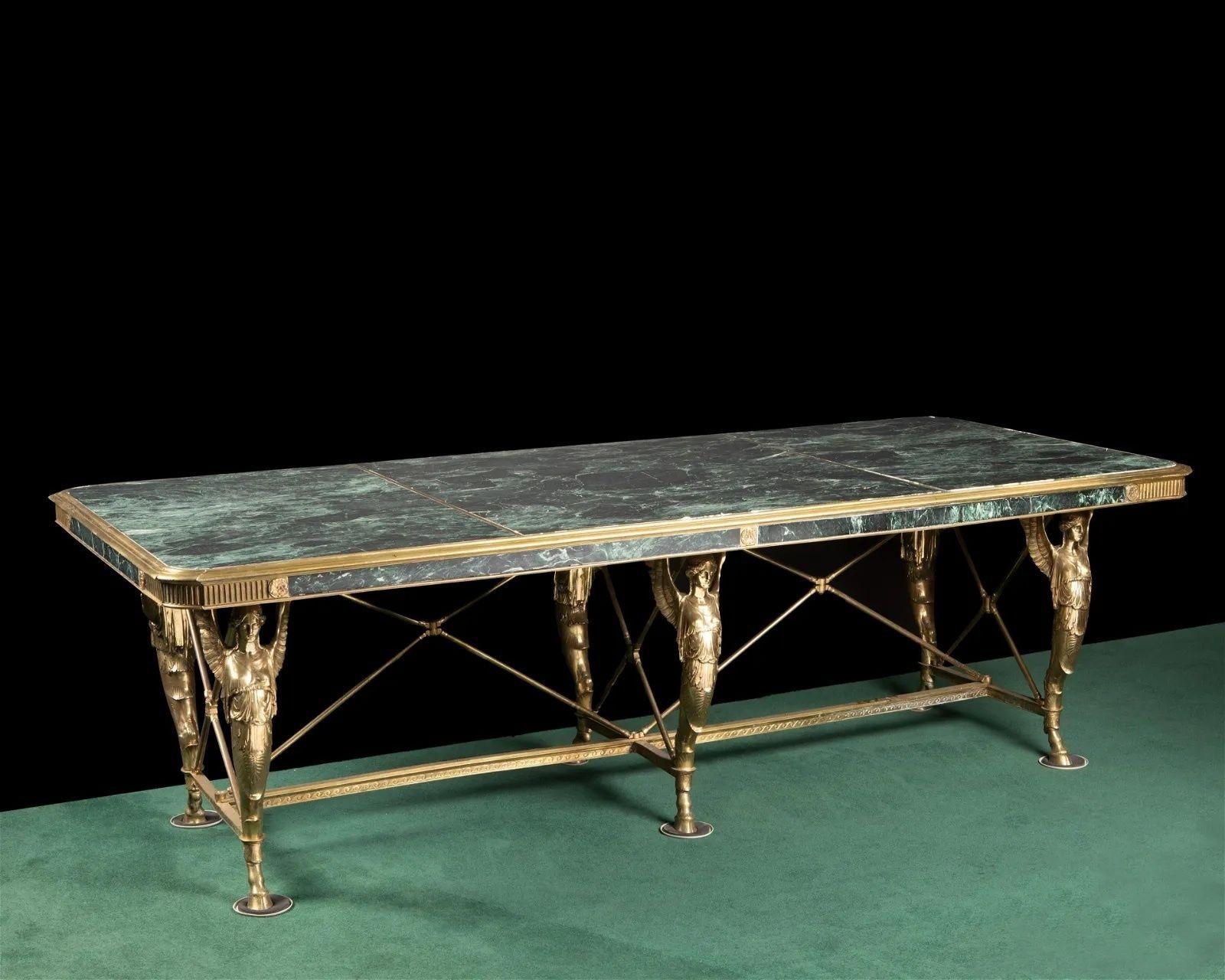 Une table de bibliothèque de style néoclassique.
Fin du 19e siècle.
Plateau marbré vert veiné, reposant sur des pieds demi-figures ailés en métal doré
Mesures : 31.5