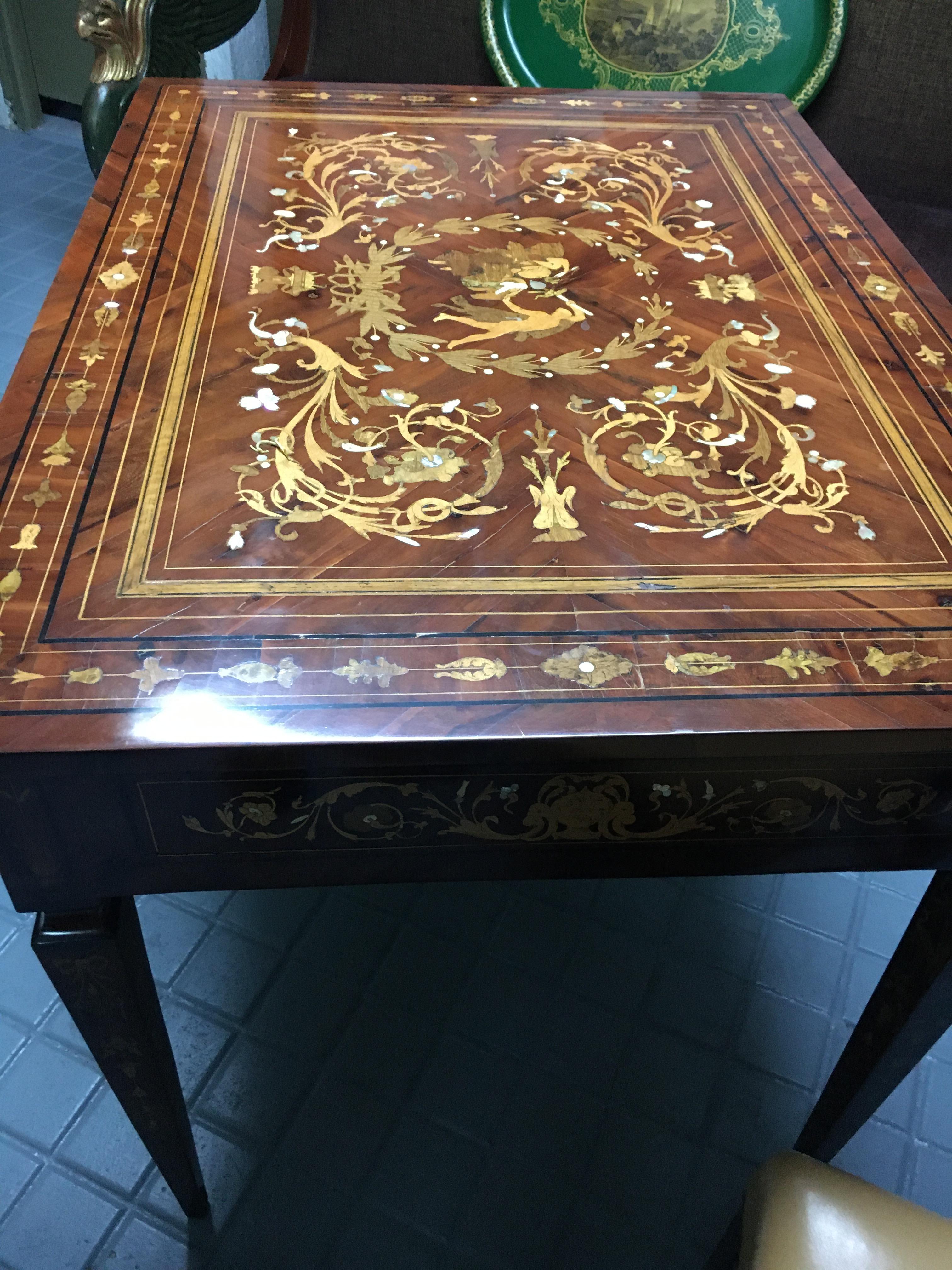 In intarsio di vari Wood, osso e madreperla.
Top con motivi floreali e arabeschi.
Ercole che combatte contro un leone al centro in alto.
Cassetto anteriore.
Lo stile di Giuseppe Maggiolini nei tessuti.


 