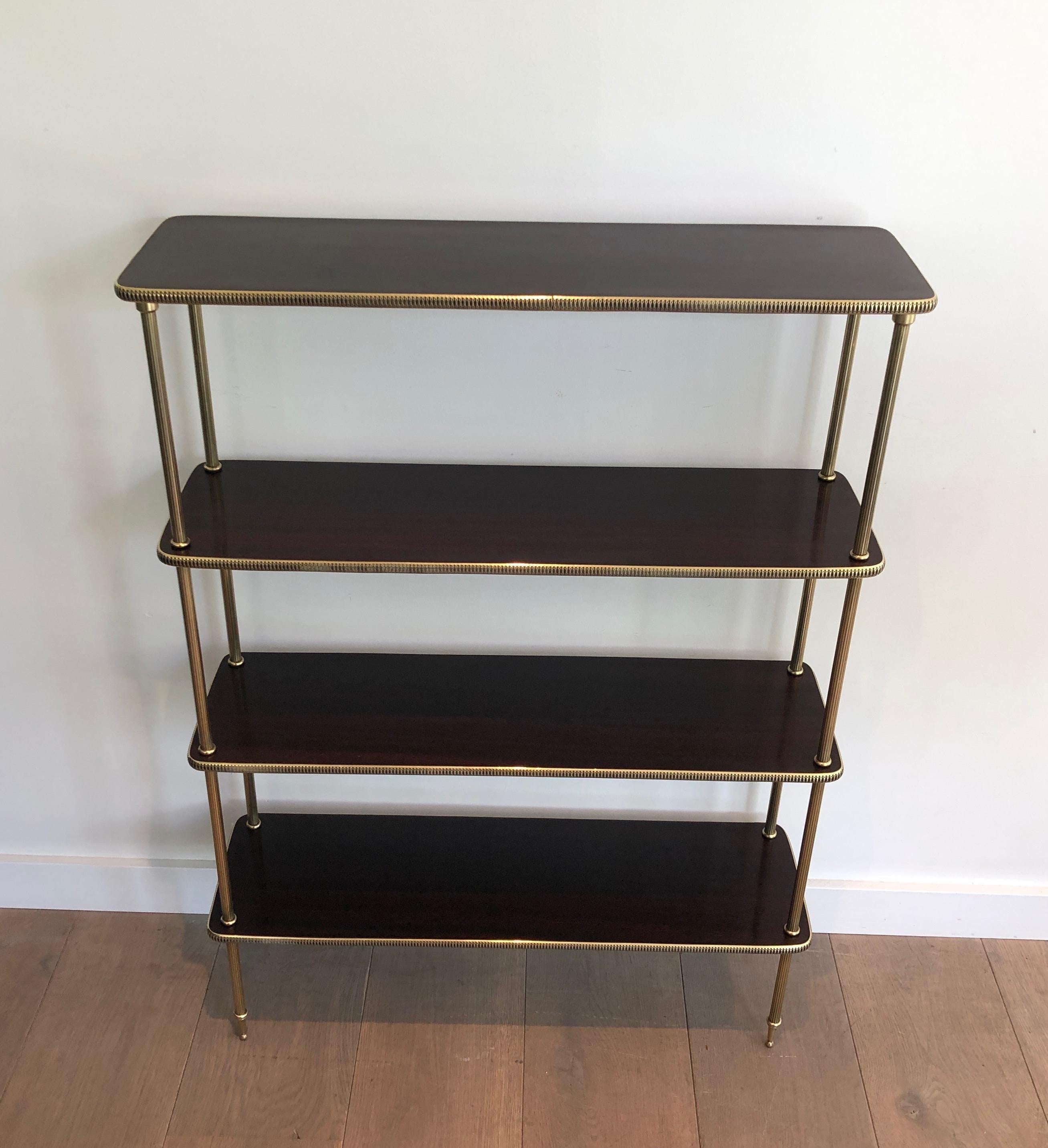 This neoclassical style shelves unit is made of mahogany and brass. This is a very elegant bookcase with 4 mahogany shelves surrounded by a brass gallery. This is a French work, circa 1940.