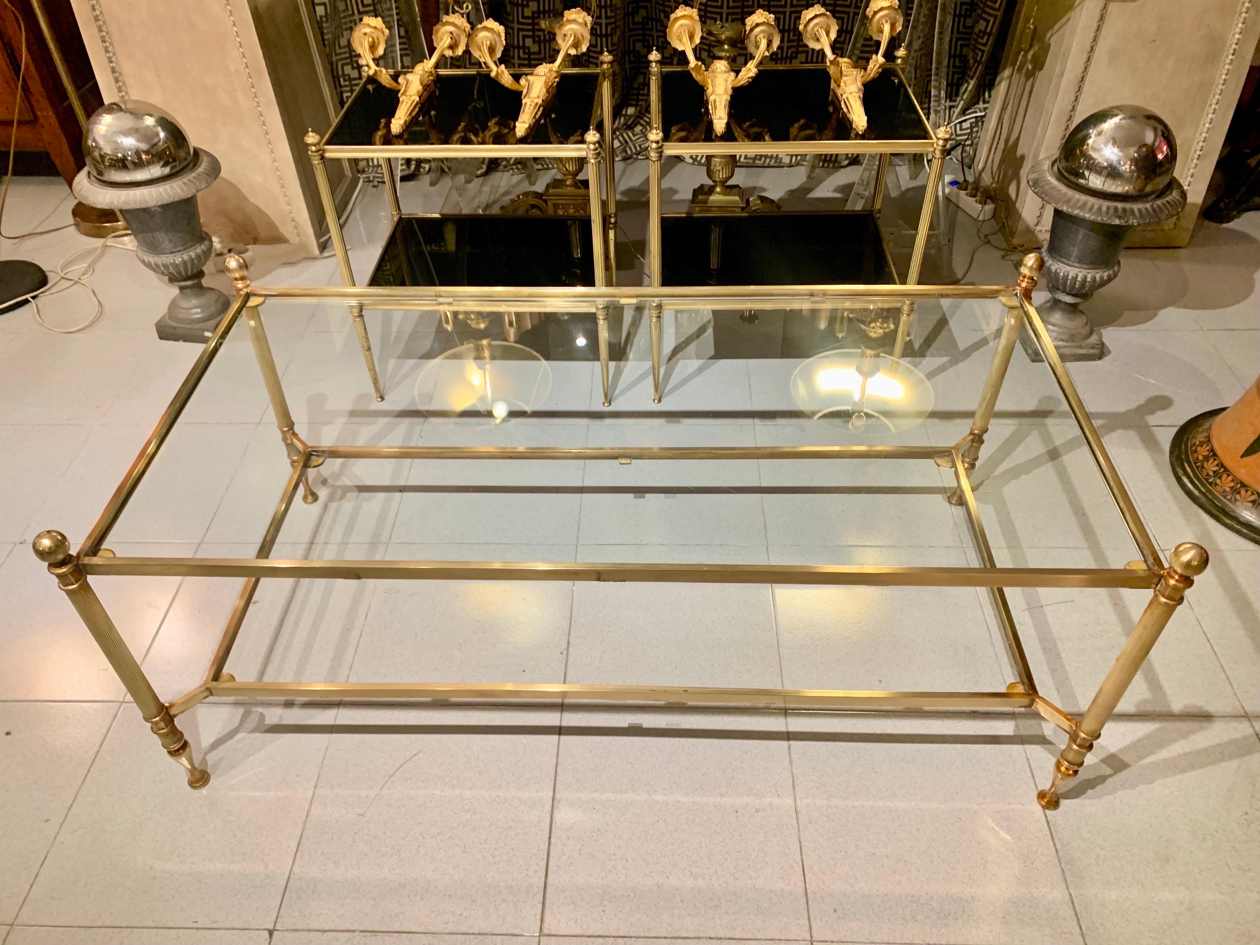 An elegant coffee or cocktail table, from the 1950s, in the style of the Maison Jansen, in gold brass and bronze, with two trays, with a transparent glass top.