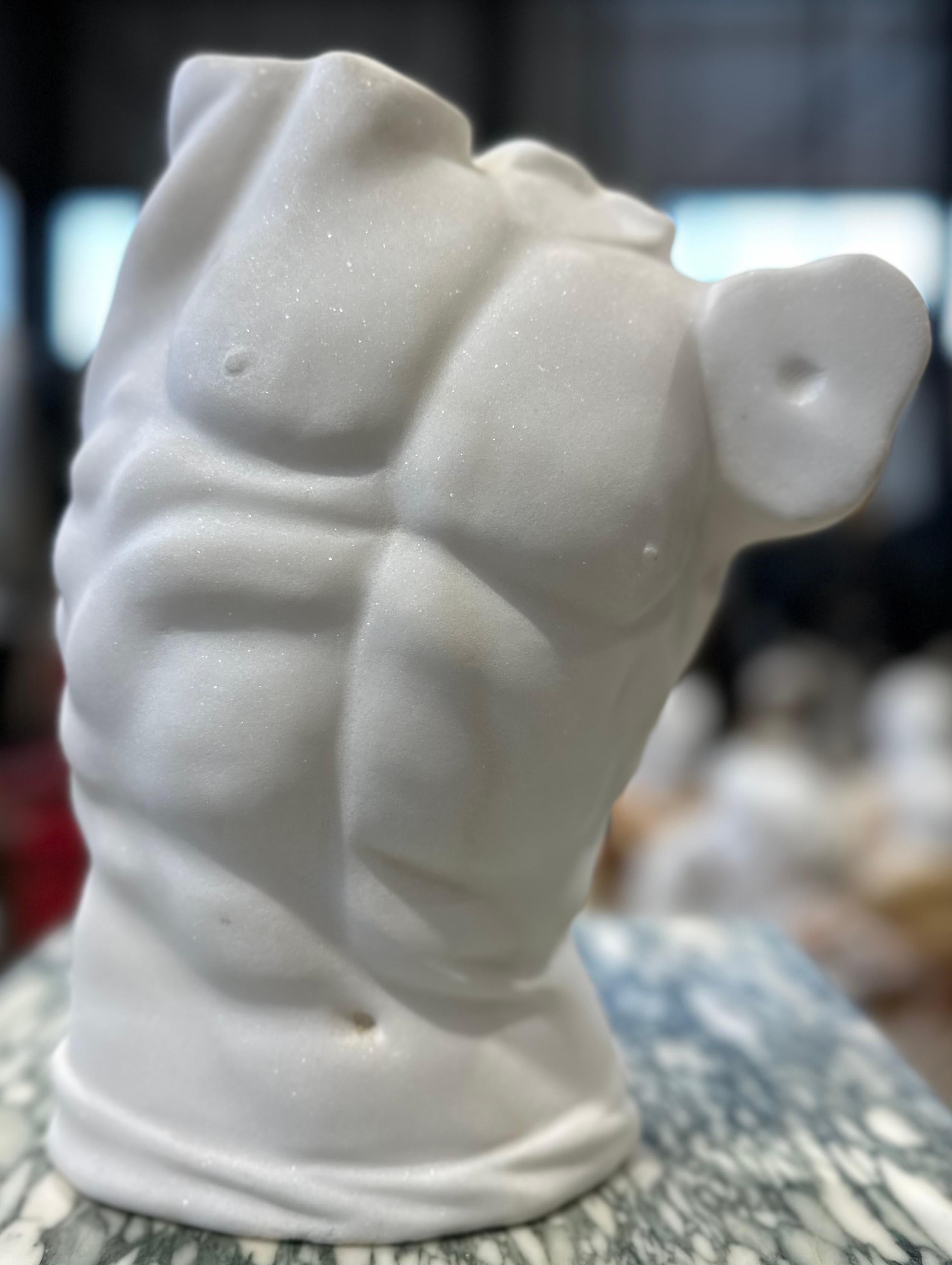 Handsomely hand carved marble male torso in white marble. The body is contoured and defined twisted into a classically inspired pose that emphasises the muscles and smoothness of the marble. A attractive piece that would be sure to draw many