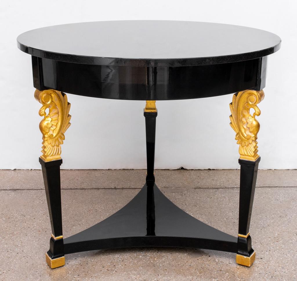 Runder Gueridon-Tisch im neoklassischen Stil aus schwarzem Lack mit schwarzer Marmorplatte, vergoldeten Schnitzereien an drei Beinen und Füßen sowie einer niedrigen Ablage. 28,5
