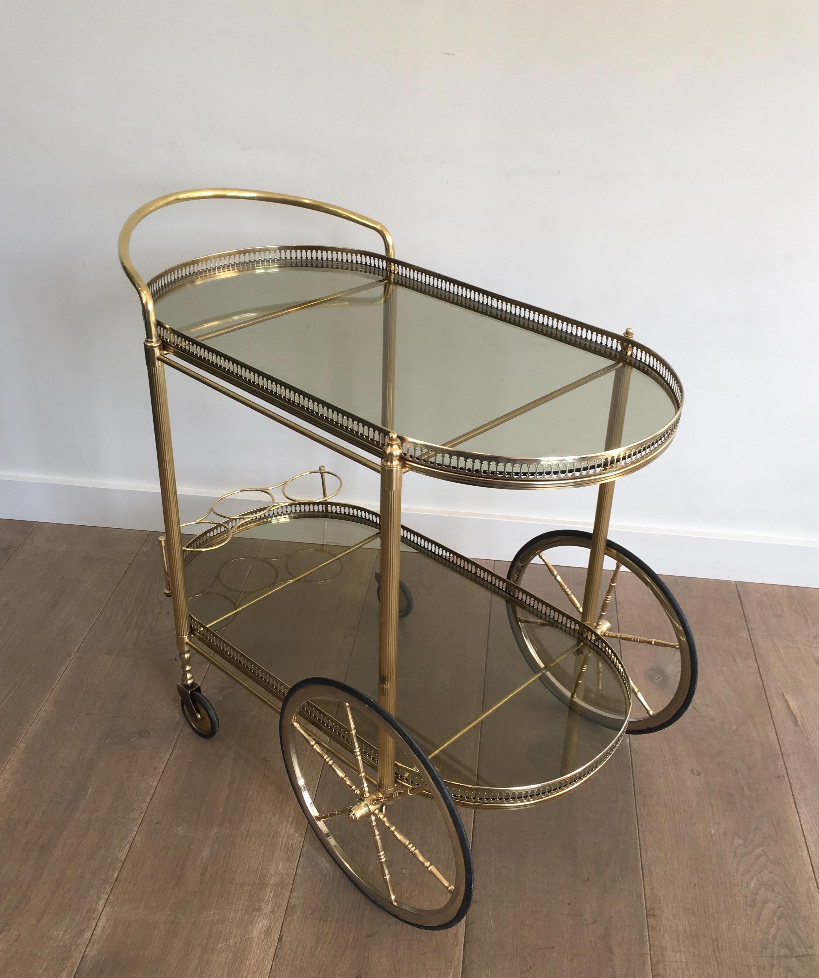 This neoclassical style oval bar car is made of brass and silver color drinks trolley with greenish smoked glass, French, circa 1970.