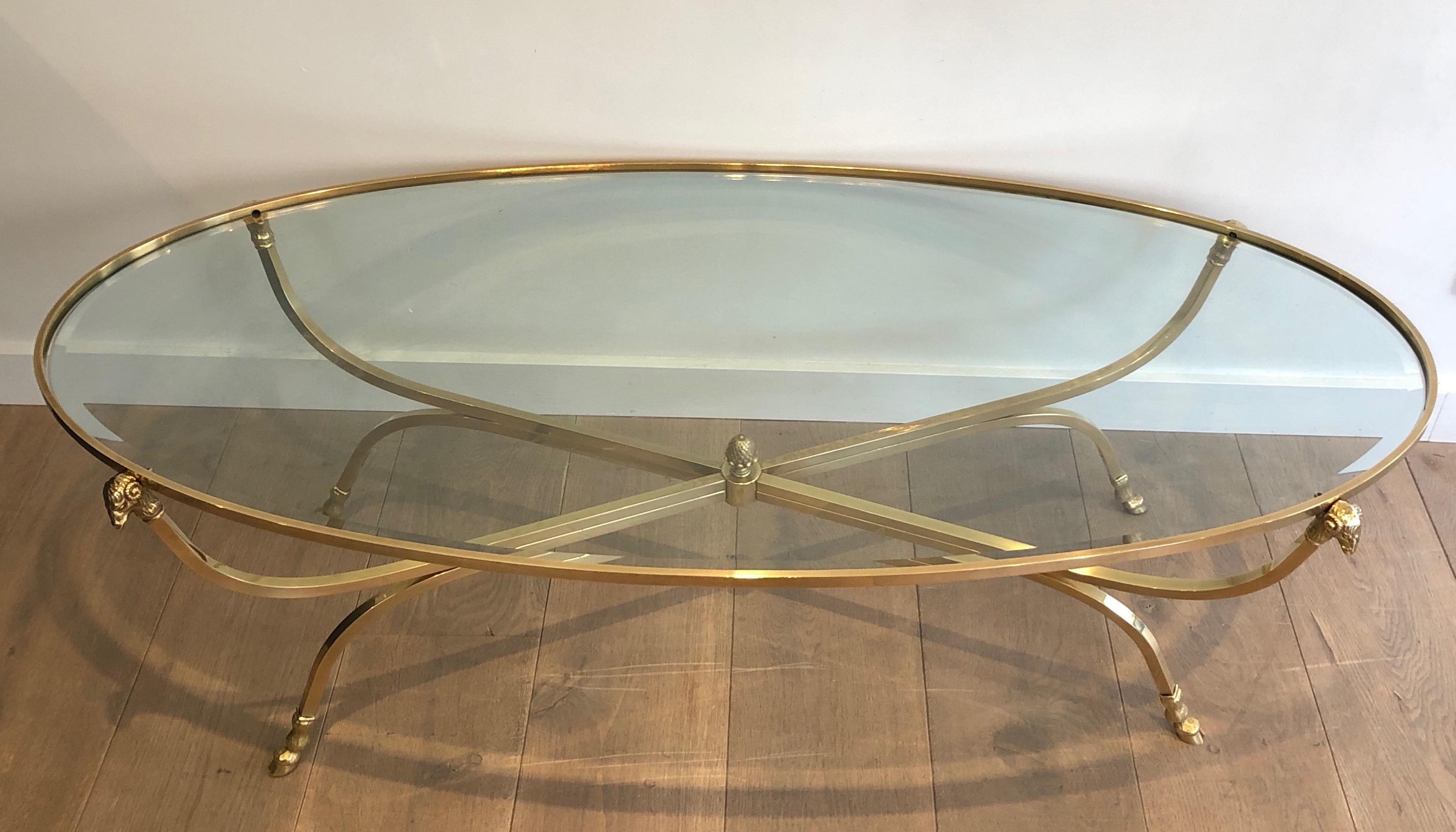 This large neoclassical style ovale coffee table is made of brass and bronze with finely chiseled ram heads and hoof. This is a French work attributed to famous French designer Maison Jansen. Circa 1940