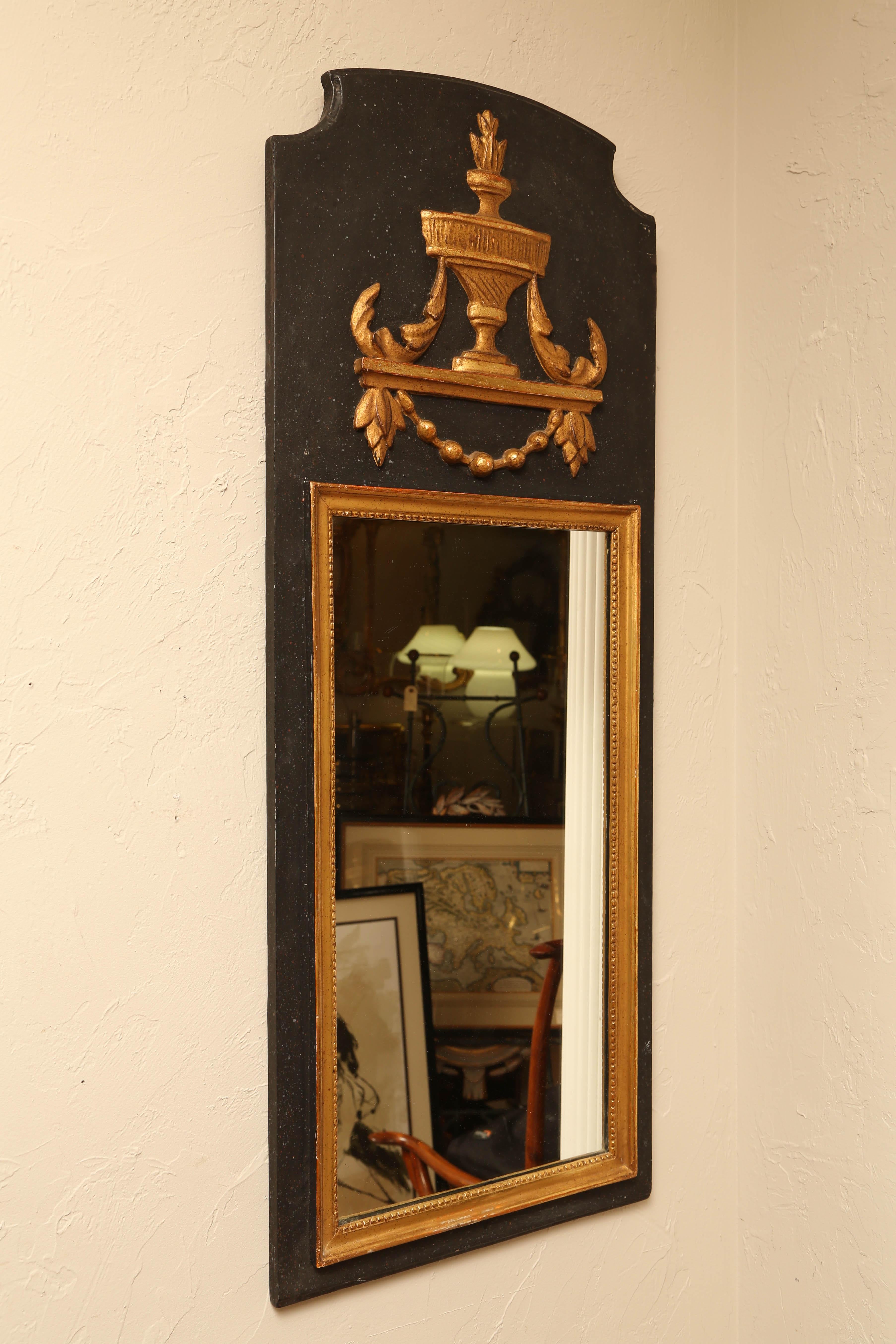 Painted and gilded neoclassical style mirror with striking embellishments.