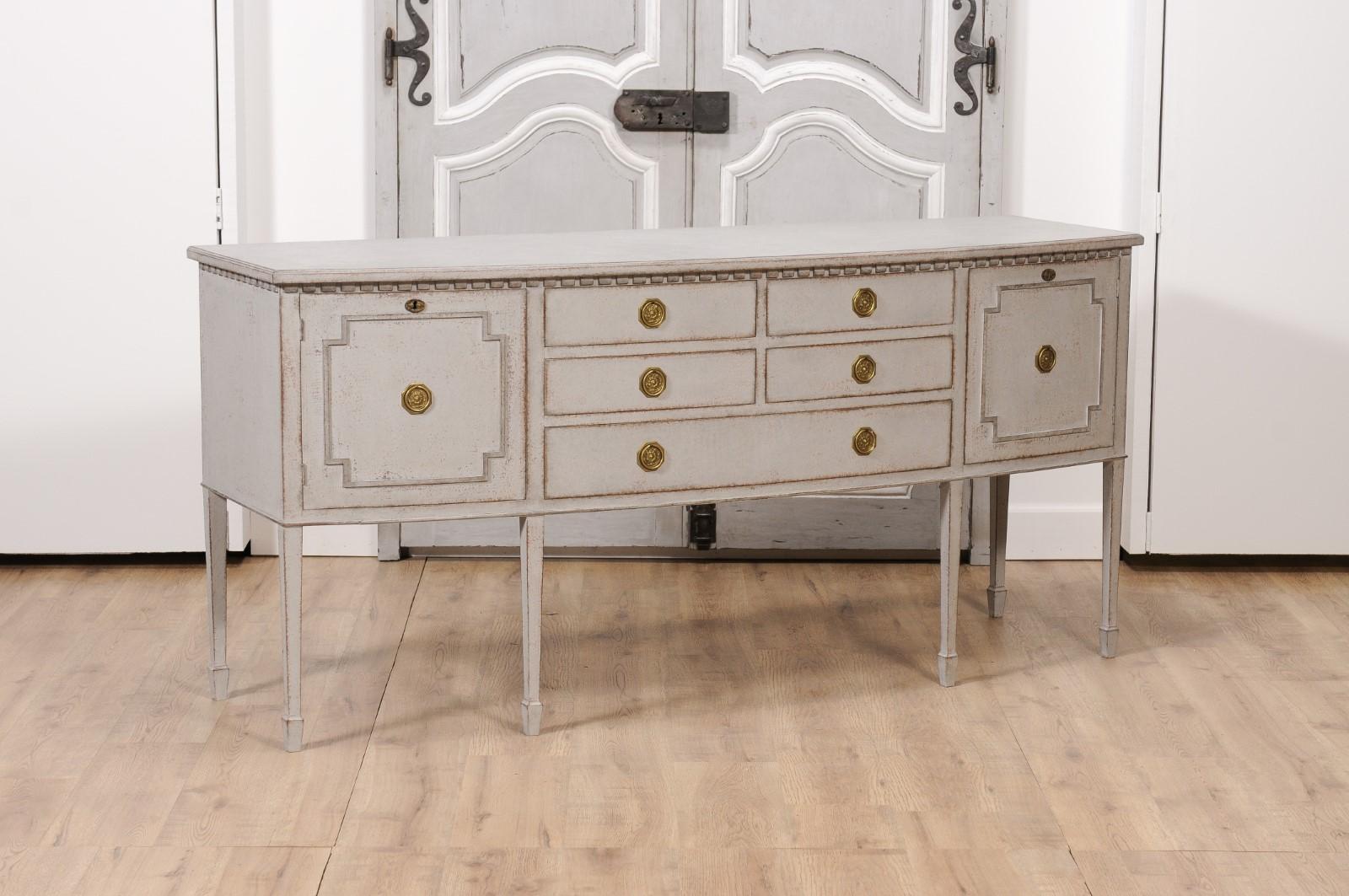 A Neoclassical style Swedish painted wood bow front sideboard from the 20th century with five drawers flanked by two doors. Immerse yourself in the elegance of the past with this Neoclassical style Swedish painted wood bow-front sideboard, dating