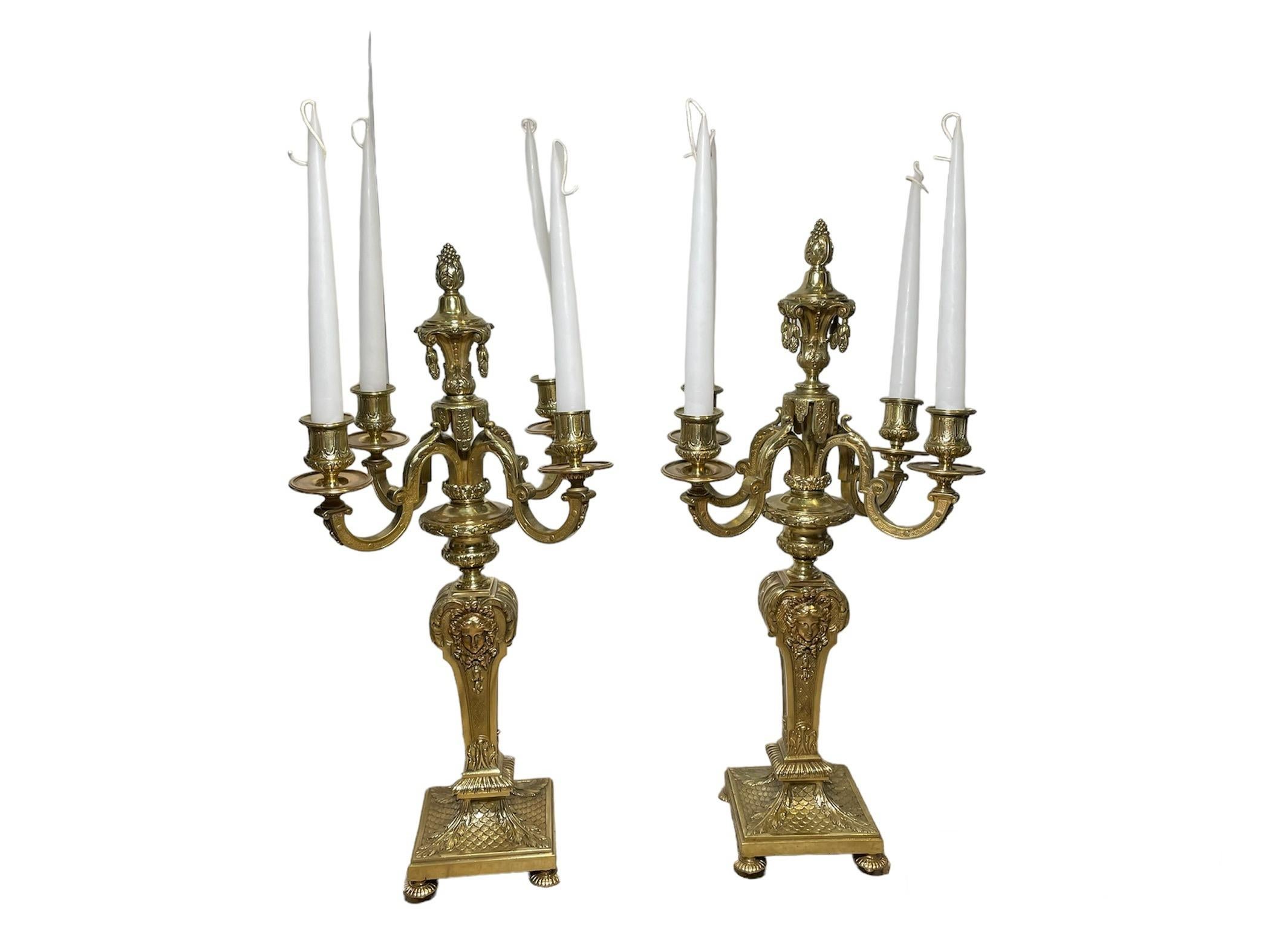 Si tratta di una coppia di candelabri in bronzo dorato in stile neoclassico. Raffigura una coppia di pesanti candelabri in bronzo con quattro bracci e quattro appliques con incise delle volute. Le applique sono dotate di gocciolatoi rotondi. I gambi