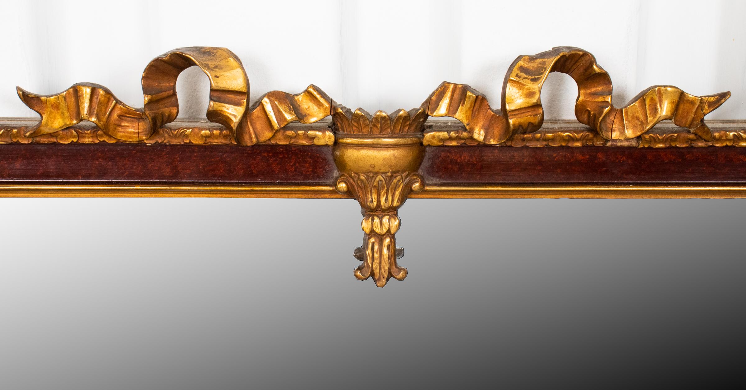 Neoclassical style parcel giltwood mirror, the crest with ribbon swag motifs. Measures: 36” H x 25” W x 2” D. Minor losses.