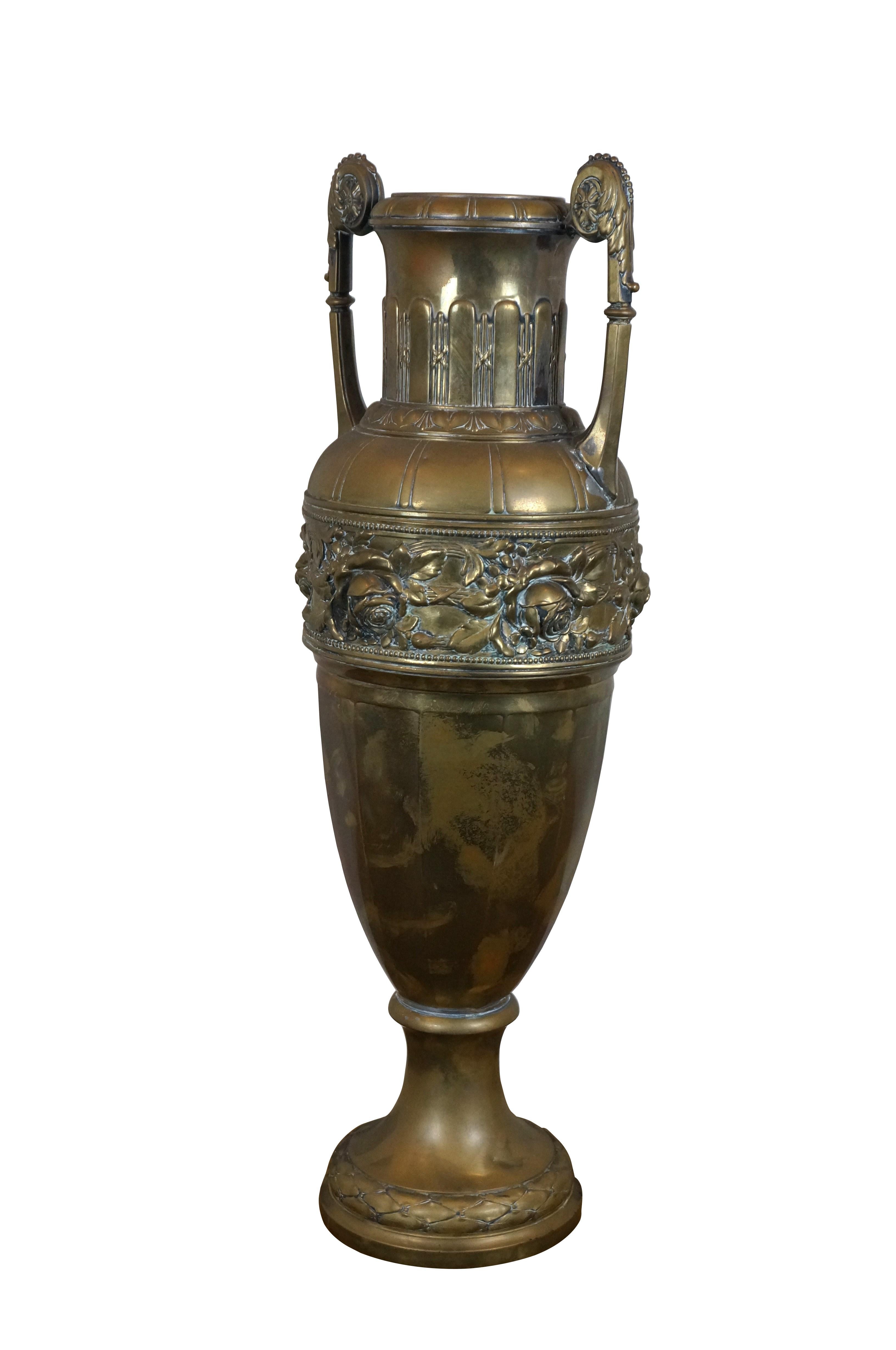 Vintage Neoclassical or Empire style tall brass urn / cassolette / amphora vase with scrolled handles and a repousse band showing a vine of roses and small blossoms winding around bundled staves.

Dimensions:
8.5