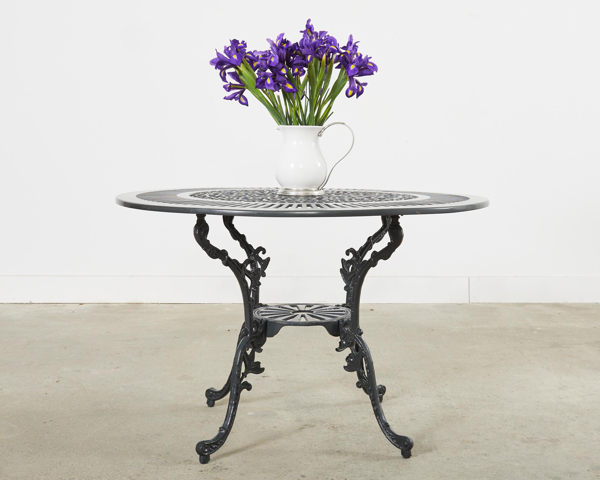 Distinctive powder coated cast aluminum patio and garden dining table featuring a dark Pompeiian green finish. Made on a small scale for four diners measuring 42 inches in diameter and 27.5 inches high. The round top has an outer ring of slat