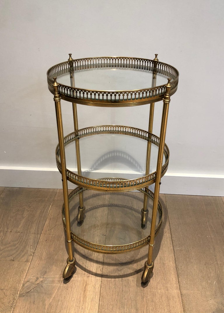 This neoclassical style 3 tiers round bar cart is made of brass with glass shelves. This is a French work attributed to Maison Jansen. Circa 1940.