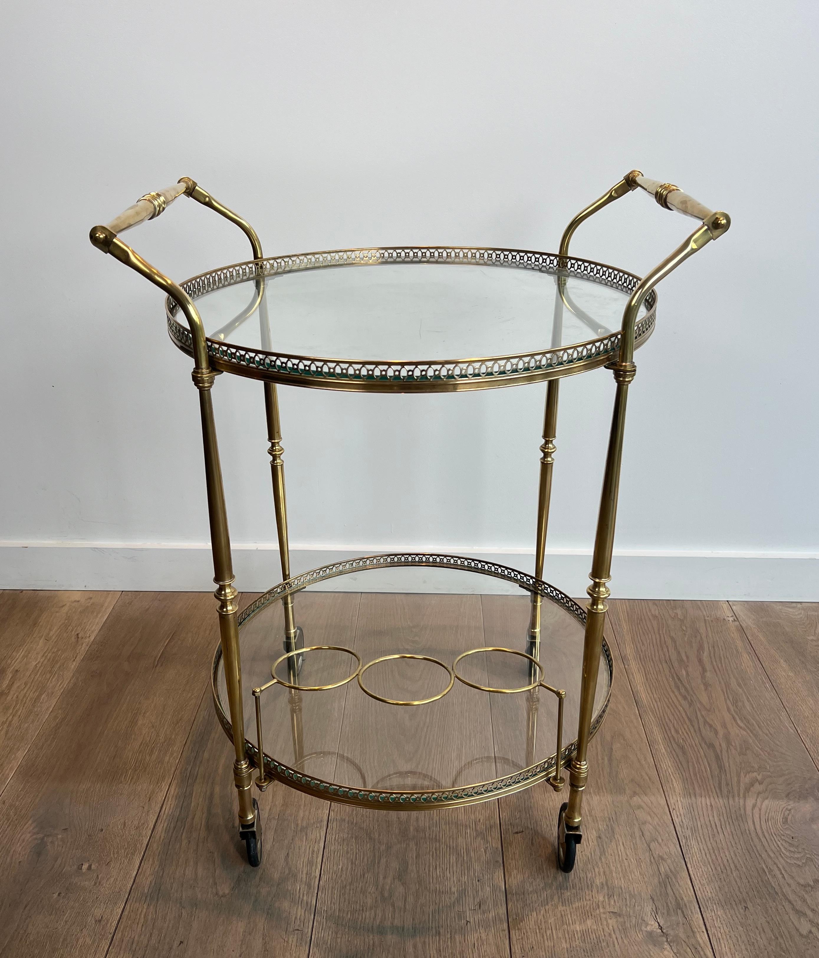 Este bonito carrito de bar redondo de estilo neoclásico es de latón y tiene dos estantes de cristal. Se trata de una obra francesa de la Maison Jansen. Alrededor de 1940