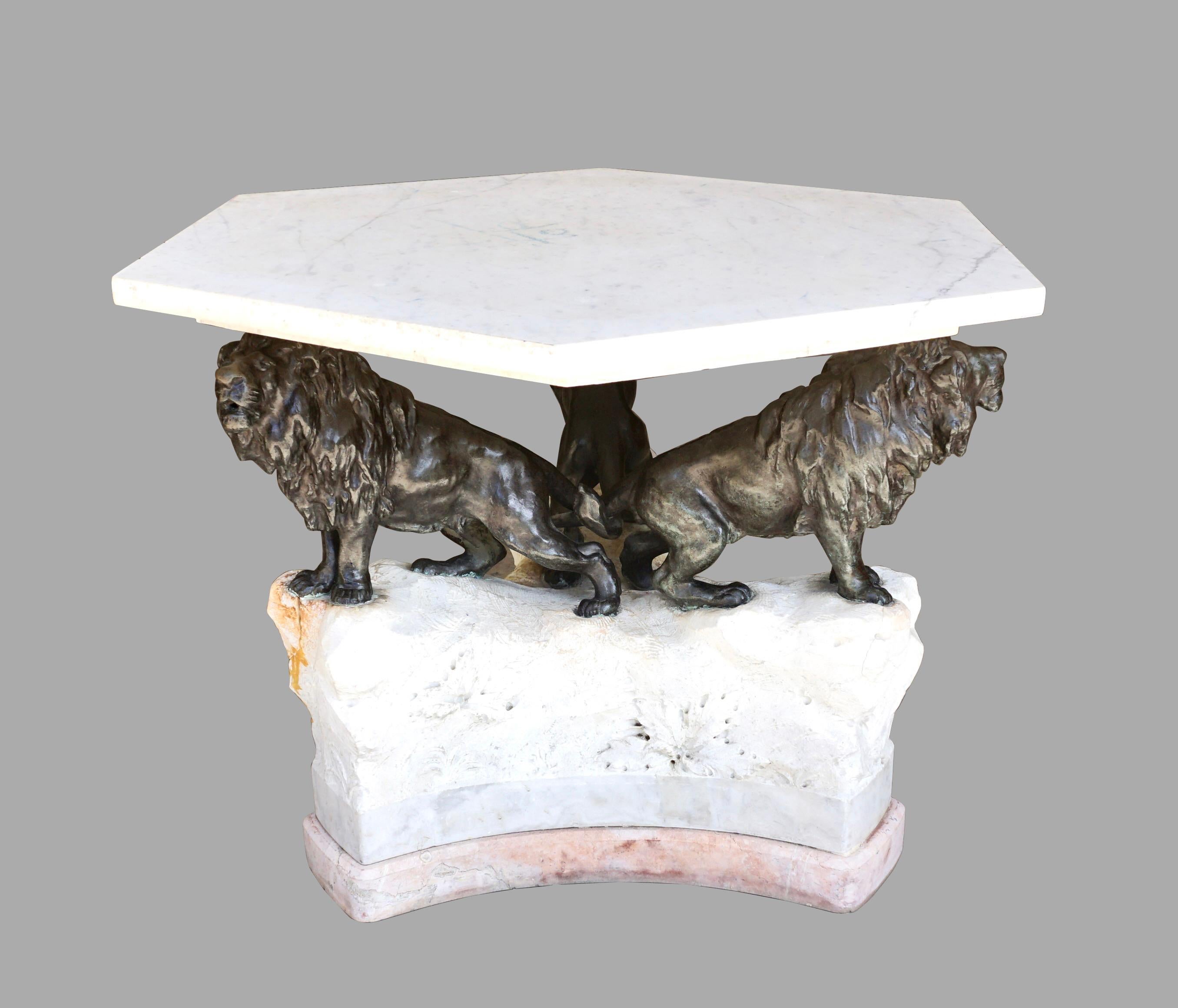 A dramatic hexagonal low table, the stone top supported by a secondary smaller stone top, all resting on a trio of well-cast bronze lions with intertwined tails on a stone base with carved leaves. This unusual piece is probably a custom design and