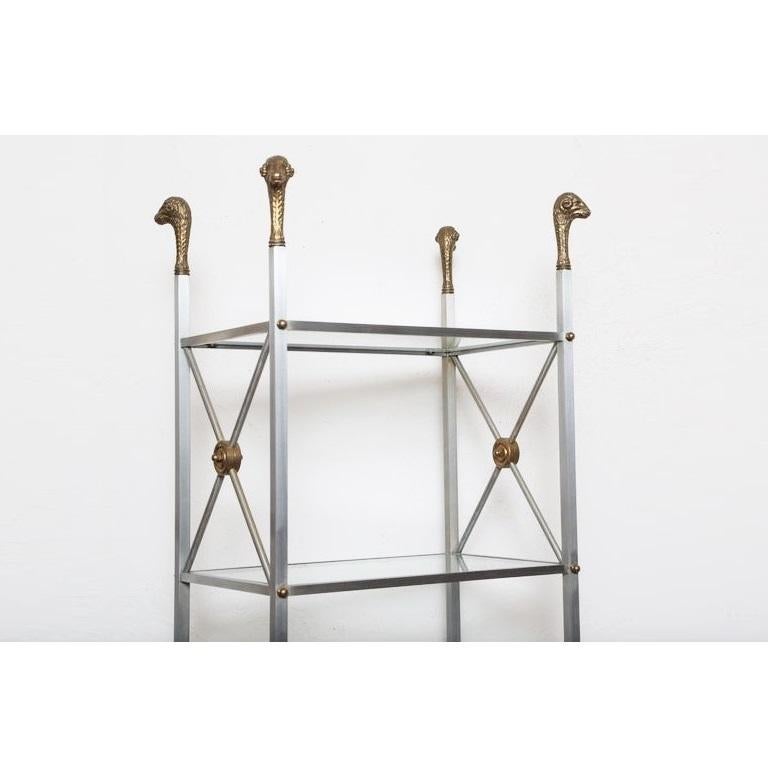 Italian Maison Jansen style étagère shelf from the mid-20th century. Steel frames with brass accents. Featuring six-tiers, each tier with glass shelf, the uprights with ram's head terminals and hoof feet. Double X-detail on both sides.