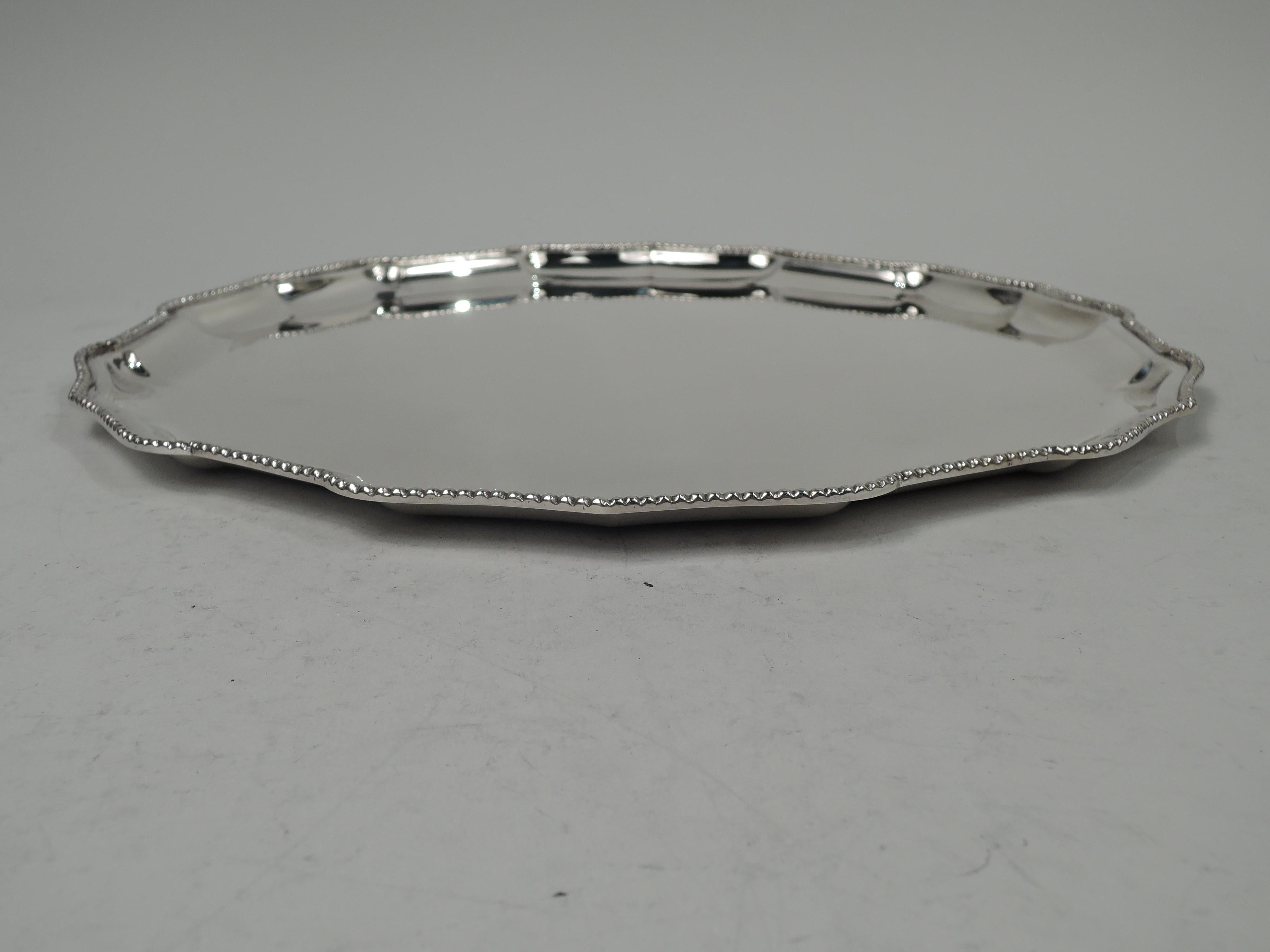 Neoclassical sterling silver tray, ca 1950. Round with beaded and curvilinear ogee rim. Nice heft with plenty of room for engraving. Marked “Silver / 925 [in oval]”. Weight: 23 troy ounces. 